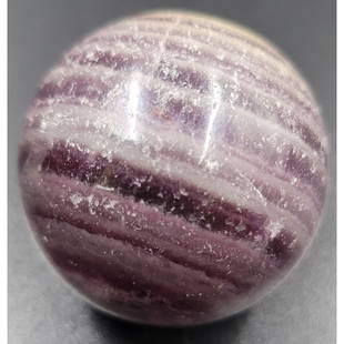 1-1/4" Agate Marble: 1-1/4" agate, purple bands cover 3/4 of the upper surface. While the base is lighter and visible forms can be seen on the interior. Near the top, there is a visible line or possible crack curving to t