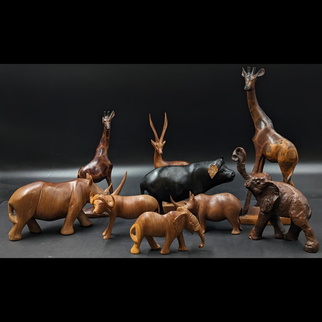 Lot Of 9 Carved Wooden African Animal Figures: Lot Of 9 Carved Wooden African Animal Figures. Please note that the black water buffalo is missing a horn and the shorter giraffe is missing an ear. Measures approx. from 3" X 4 1/2" to 11 1/2" X 4 1/
