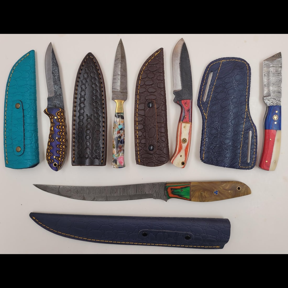 5Pc Hand Made Damascus Steel Knives And Sheaths: **DUE TO THIS LOT BEING CLASSED AS A WEAPON IT MUST BE PAID VIA BANK WIRE TRANSFER OR CERTIFIED CHECK.** 5Pc Hand Made Damascus Steel Knives And Sheaths. knives measure approx. 14" X 1.5", 8" X 1.25",