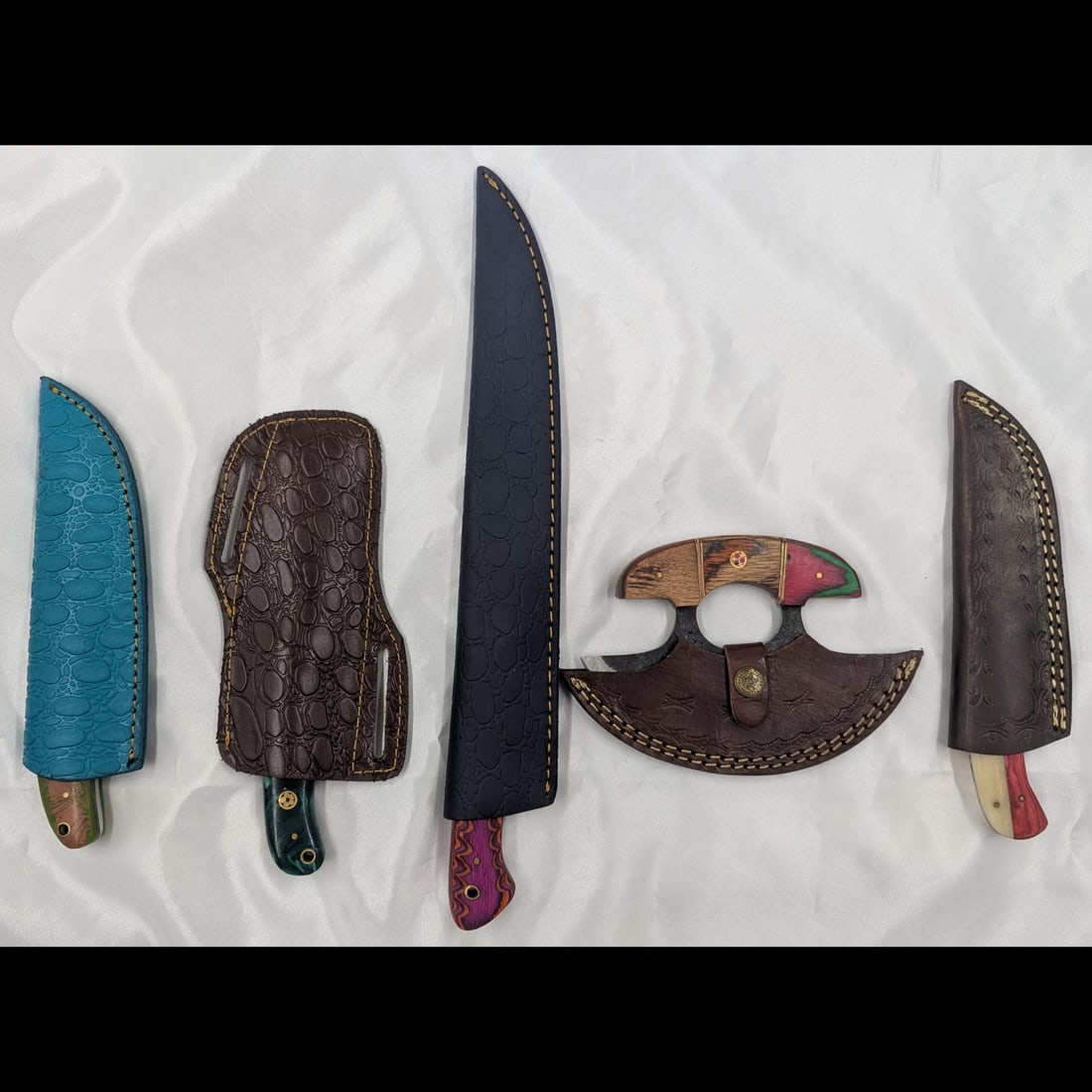 5Pc Hand Made Damascus Steel Knives And Sheathes: **DUE TO THIS LOT BEING CLASSED AS A WEAPON IT MUST BE PAID VIA BANK WIRE TRANSFER OR CERTIFIED CHECK.** 5Pc Hand Made Damascus Steel Knives And Sheathes. Knives measure 6", 8", 8", 8", and 14" long.