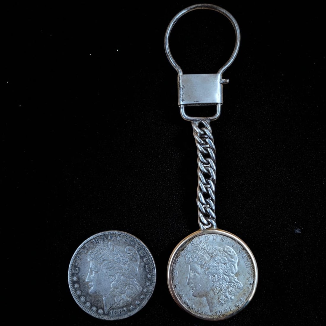 1884 And 1921 Morgan Silver Dollars: **THIS LOT CAN NOT BE SHIPPED TO MEXICO OR CHINA** 1884 And 1921 Morgan Silver Dollars. The 1921 silver dollar is on a chain. Coins measure approx. 1.5" diameter. Please copy and pas