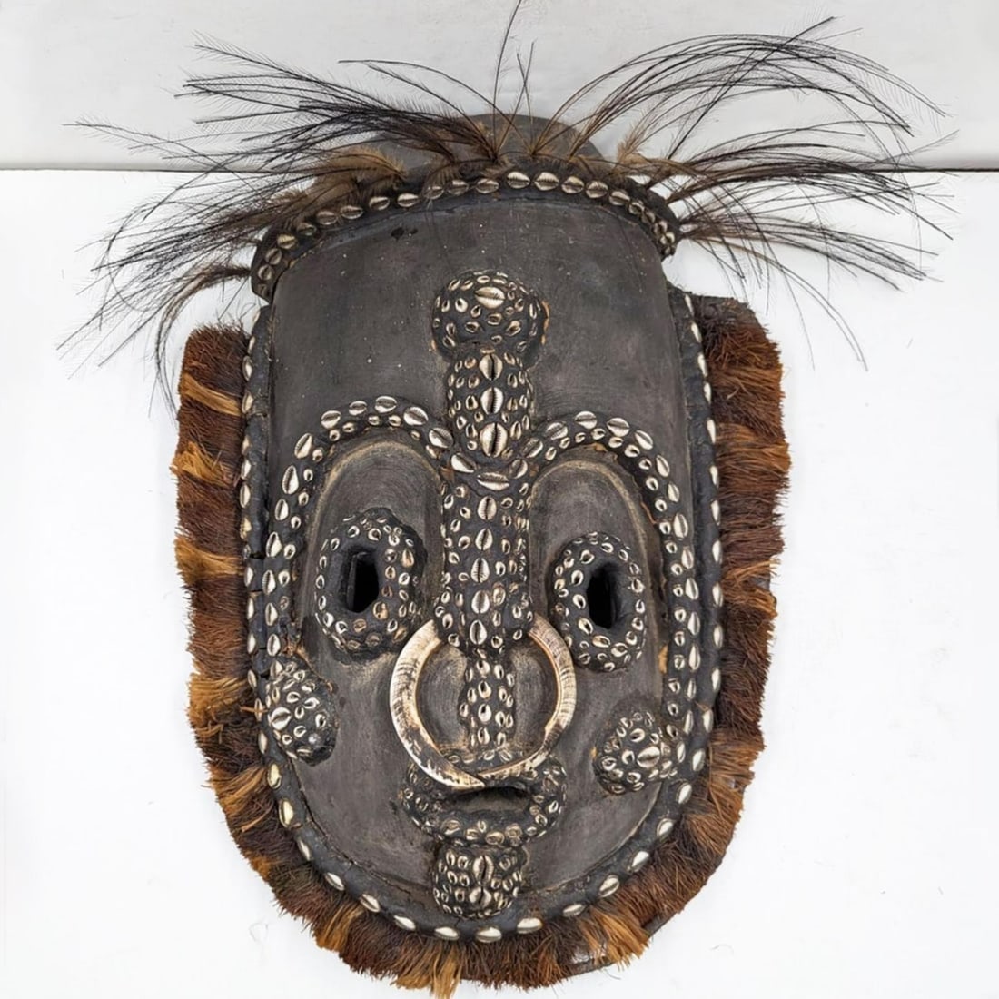 Large Papua New Guinea Iatmul Sepik Region Carved Wood Mask With Shells, Tusks, And Feathers: Large Papua New Guinea Iatmul Sepik Region Carved Wood Mask With Shells, Tusks, And Feathers. Measures approx. 19 1/2" X 16". Provenance: Artifacts were acquired from a private estate in South Florida