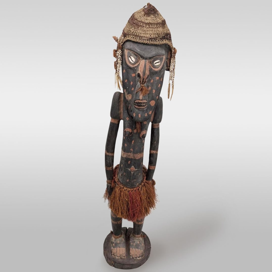 Large Antique Papua New Guinean Carved Wood Tribal Ancestor Figure With Headdress, Sepik River: Large Antique Papua New Guinean Carved Wood Tribal Ancestor Figure With Headdress And Grass Skirt, Sepik River. Measures approx. 43" X 8". Provenance: Artifacts were acquired from a private estate in