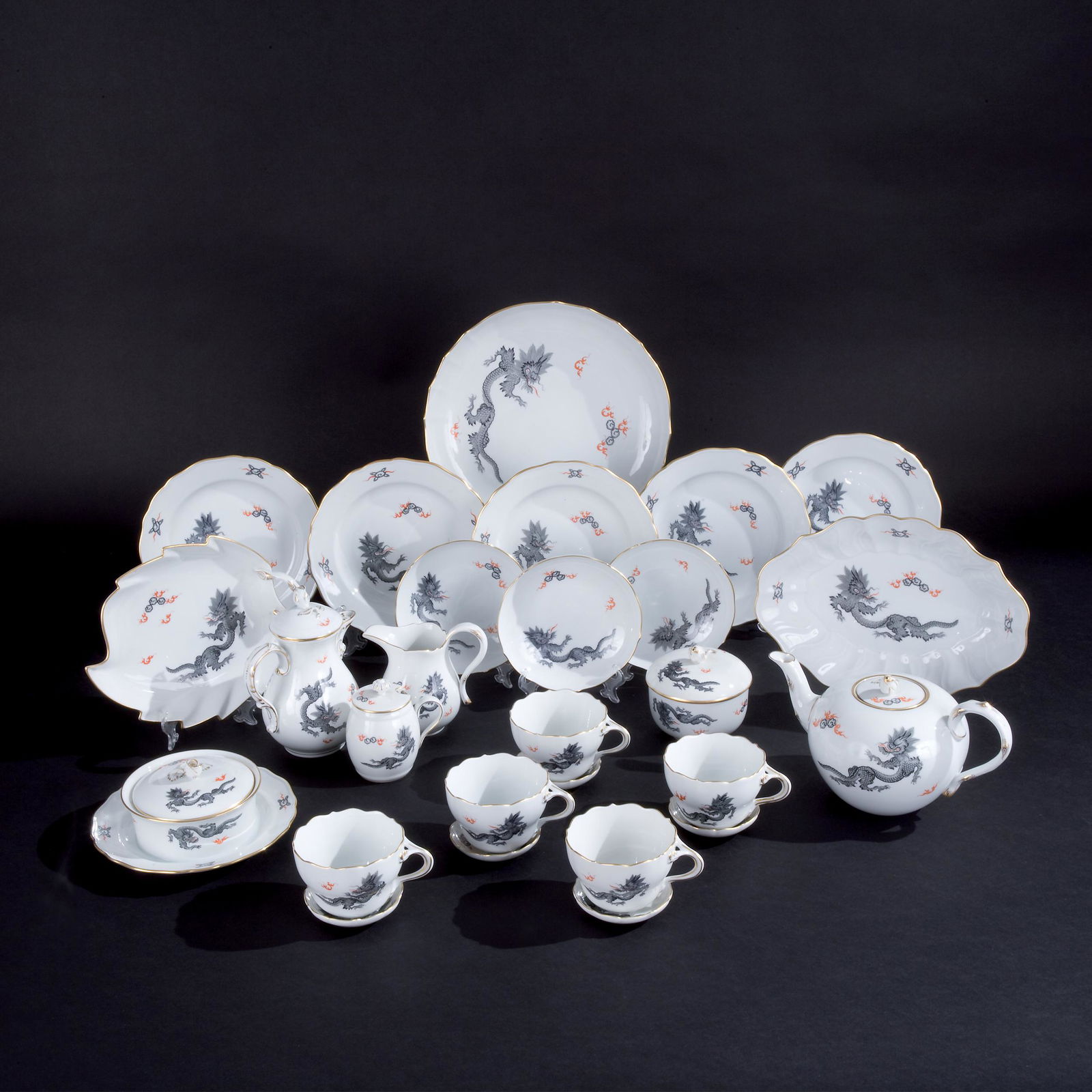 A white and grey dragon tea and cofee service: Meissen, '50s, comprising 5 cups and saucer, 1 teapot, 1 coffeepot, i small ewer and cover, 1 milk jug, 1 sugar bowl and cover, i round tray, 1 leaf bowl, 1 small oval tray, 6 cake plates and 6 ashtra