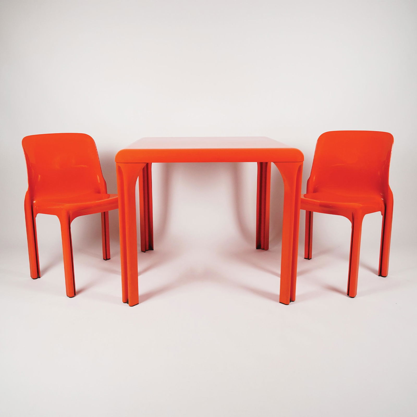 An Italian orange plastic Selene table and 2 chairs: Vico Magistretti for Artemide, 1969, the table 71by82cm., the chairs 76x47x38 each
