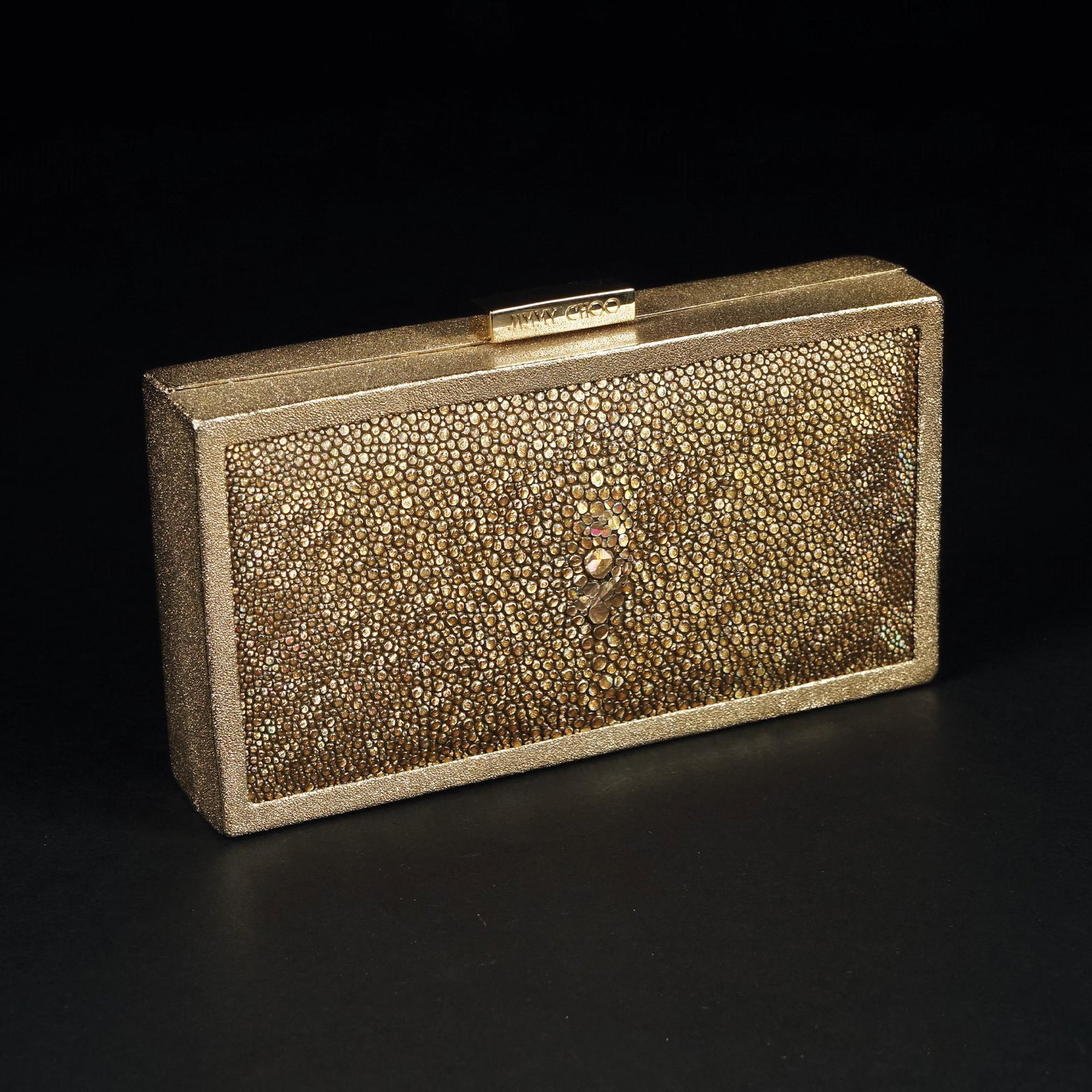 Jimmy Choo: a rectangular clutch in stingray leather with golden scales with a metal frame also golden; interior in beige satin, 3x15x8cm.