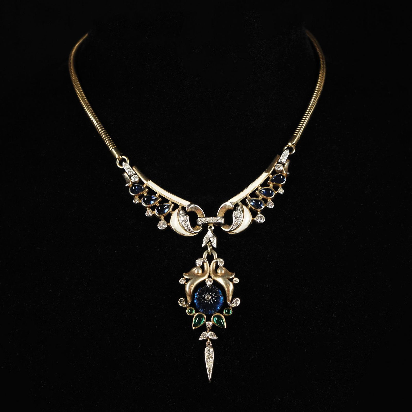 Trifari, Krussman & Fishel: An American necklace from the Mughal collection, in gilt and partly enamelled metal, rhinestones and glass of different cuts simulating sapphire and emerald, 1965 circa, 37cm. long