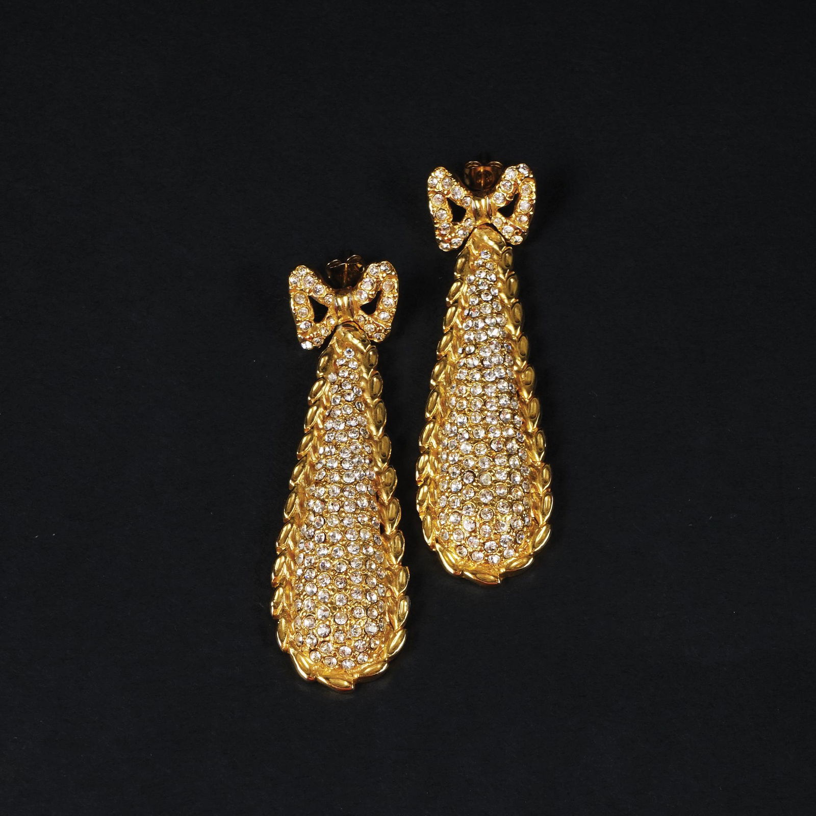 Ugo Correani: a pair of drop earrings with gilt metal bow and rhinestones.1980 circa, possibly made for Gianni Versace, 7,5cm. high each