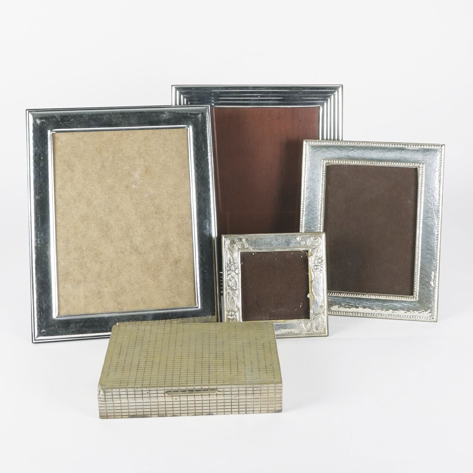 4 silver coated frames and a cigarette box: the frames: total size from 14by14cm. to 30,5by24,5cm.; the box 4x20x13cm. (dents)