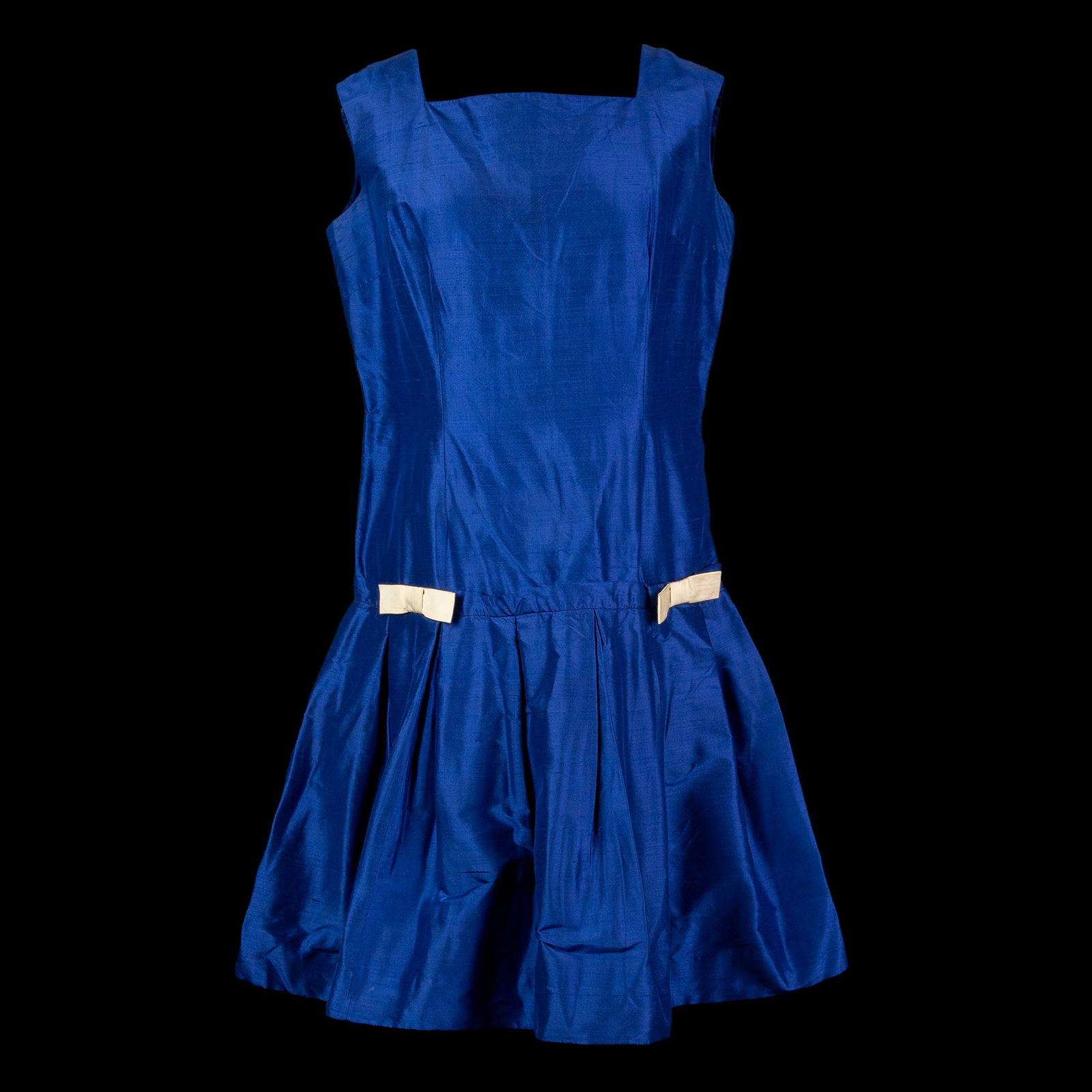 Suit: low-waisted, in bluette silk shantung; pleated skirt embellished with flat white fabric bows.'30s. Please note that each lot may have defects, stains or imperfections not noted in the catalog.