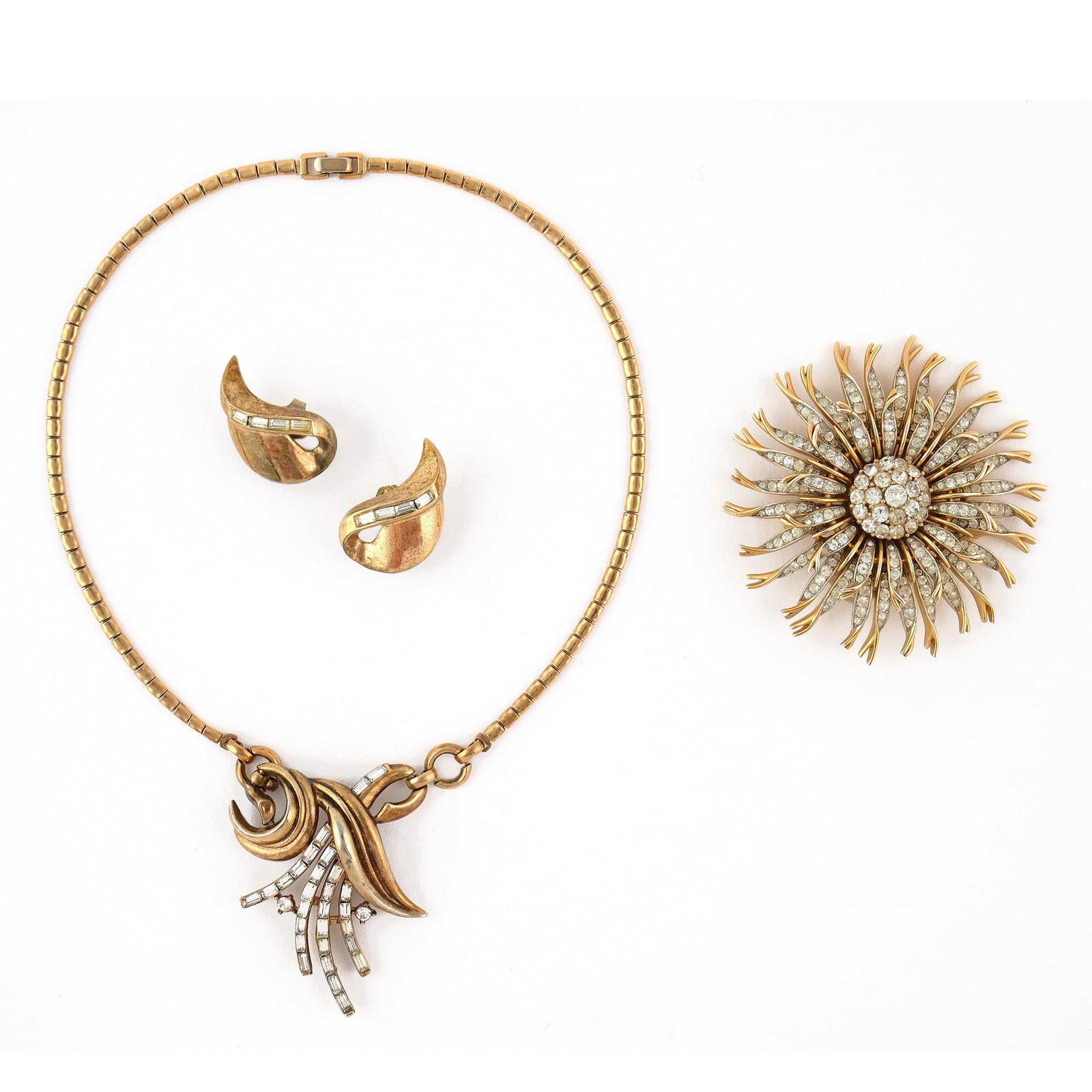 Trifari: lot of a flower brooch, a pair of earrings and a necklace, in gilt metal with rhinestone trimmings.'50s, the brooch: d. cm. 6; the necklace: l. cm. 39. Please note that each lot may have defects, stai