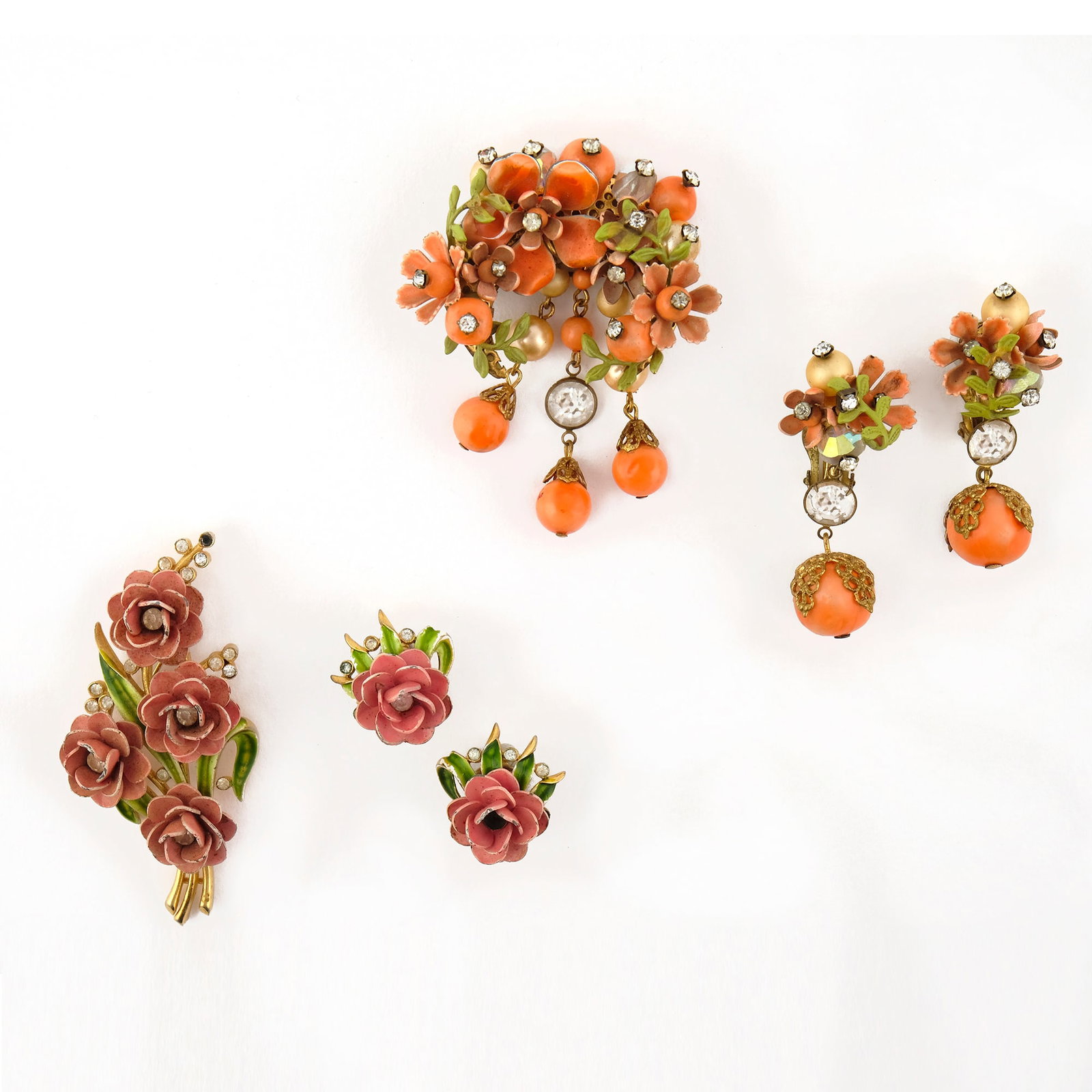 Trifari: a gilt and enamelled metal demi-parure comprising a brooch and pair of earrings chiseled with rose branches with rhinestone trimmings.'50s, the brooch: h. cm. 7 TOGETHER WITH another demi-parure of di