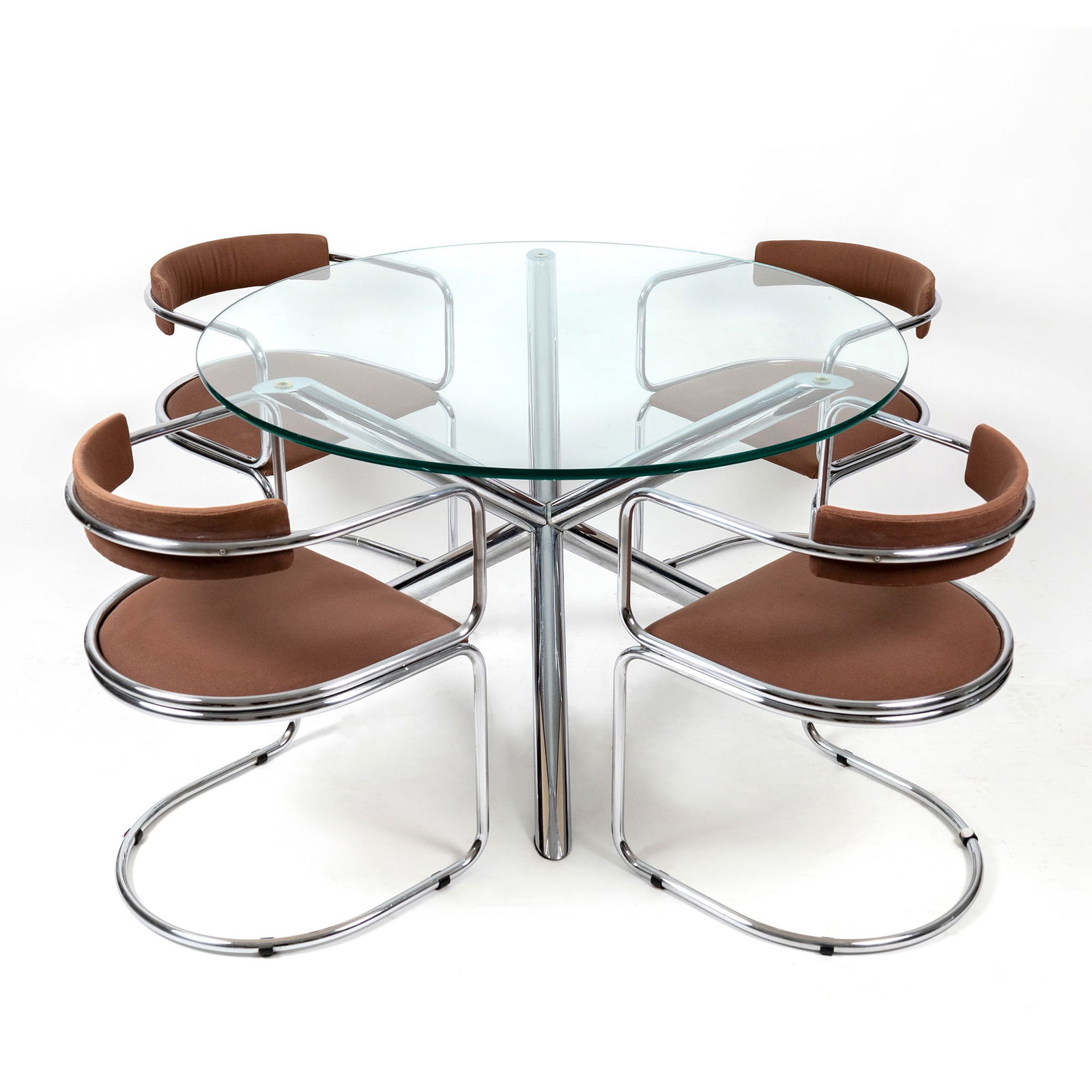Table and four chairs, 1970s: the table with tubular chromed metal structure and circular glass top; the tub chairs with chromed metal structure covered in brown fabric; the table: cm. 70x120; the chairs: cm. 70x51x46