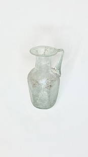 Ancient Roman Translucent Glass Jug: Title/Medium: Ancient Roman Translucent Glass Jug Origin/Year: Rome, 4th Century BCE Dimensions: Height 11 cm Condition: Weathered surface indicative of age Provenance: Ancient Roman artifact