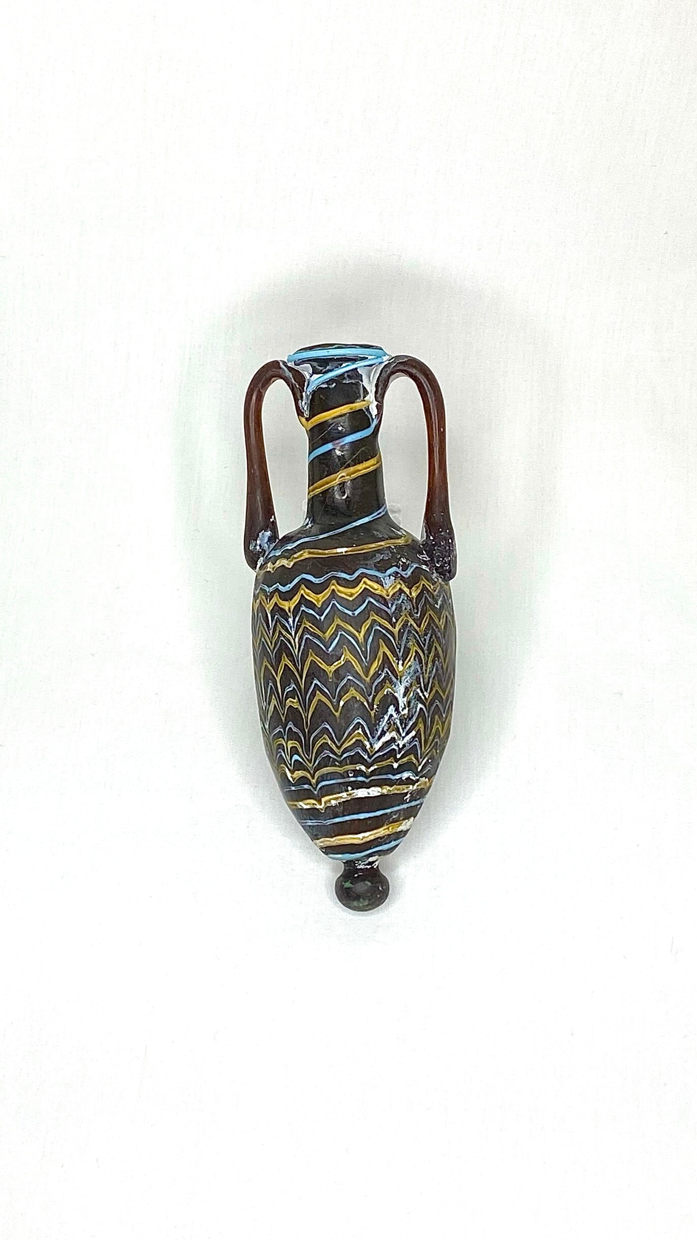 Ancient Phoenician Glass Amphora, 2nd Century BC: Title/Medium: Ancient Phoenician Glass Amphora Origin/Year: Phoenicia, 2nd Century BC Dimensions: Height: 16 cm, Width: 6 cm Condition: Excellent, minor signs of age Provenance: Acquired from a privat