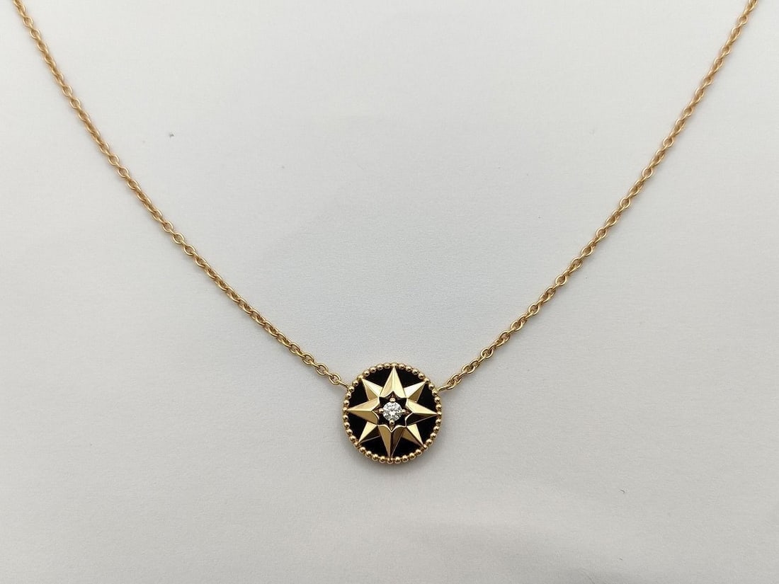 Dior Rose des Vents Black Onyx Diamond 18K Yellow Gold Necklace: Elegant Dior Rose des Vents necklace crafted in 18K yellow gold featuring the Maison's iconic compass rose motif. The medallion design is set against deep black onyx and accented with a central diamon