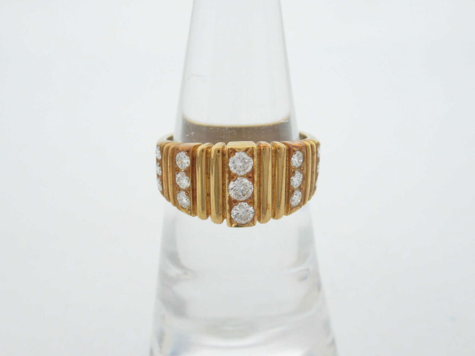 Structural Diamond 18K Yellow Gold Ribbed Band Ring: Description: Elegant ring crafted in 18K yellow gold featuring a structured ribbed band design accented with round brilliant-cut diamonds. The diamonds are set across the front of the ring, adding spa