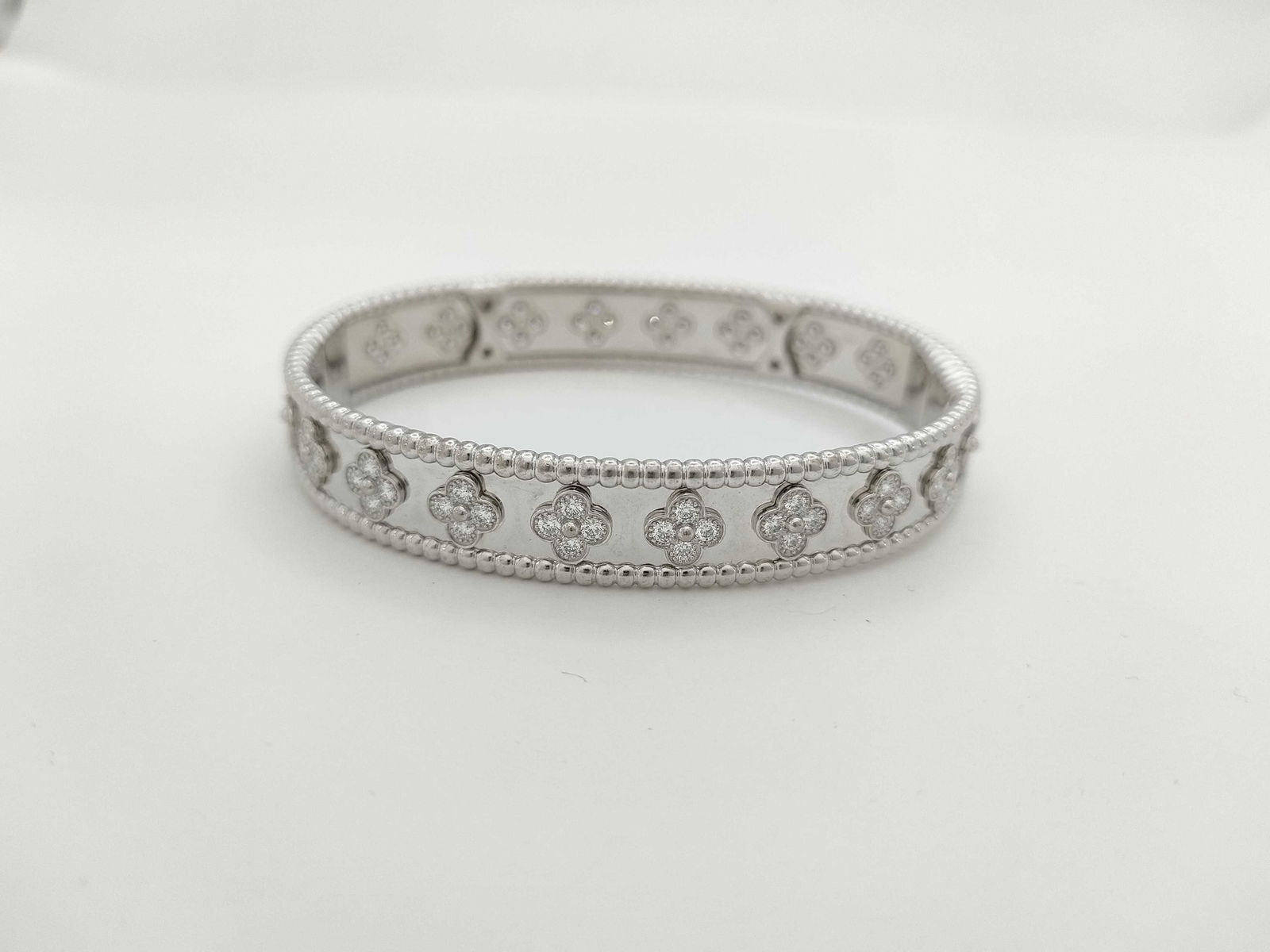Van Cleef & Arpels Perlee Clover Diamond 18K White Gold Bangle Bracelet: This elegant Van Cleef & Arpels Perlee bangle bracelet is crafted in solid 18K gold and features brilliant diamonds set within the collection's signature beaded gold design. The refined form reflects