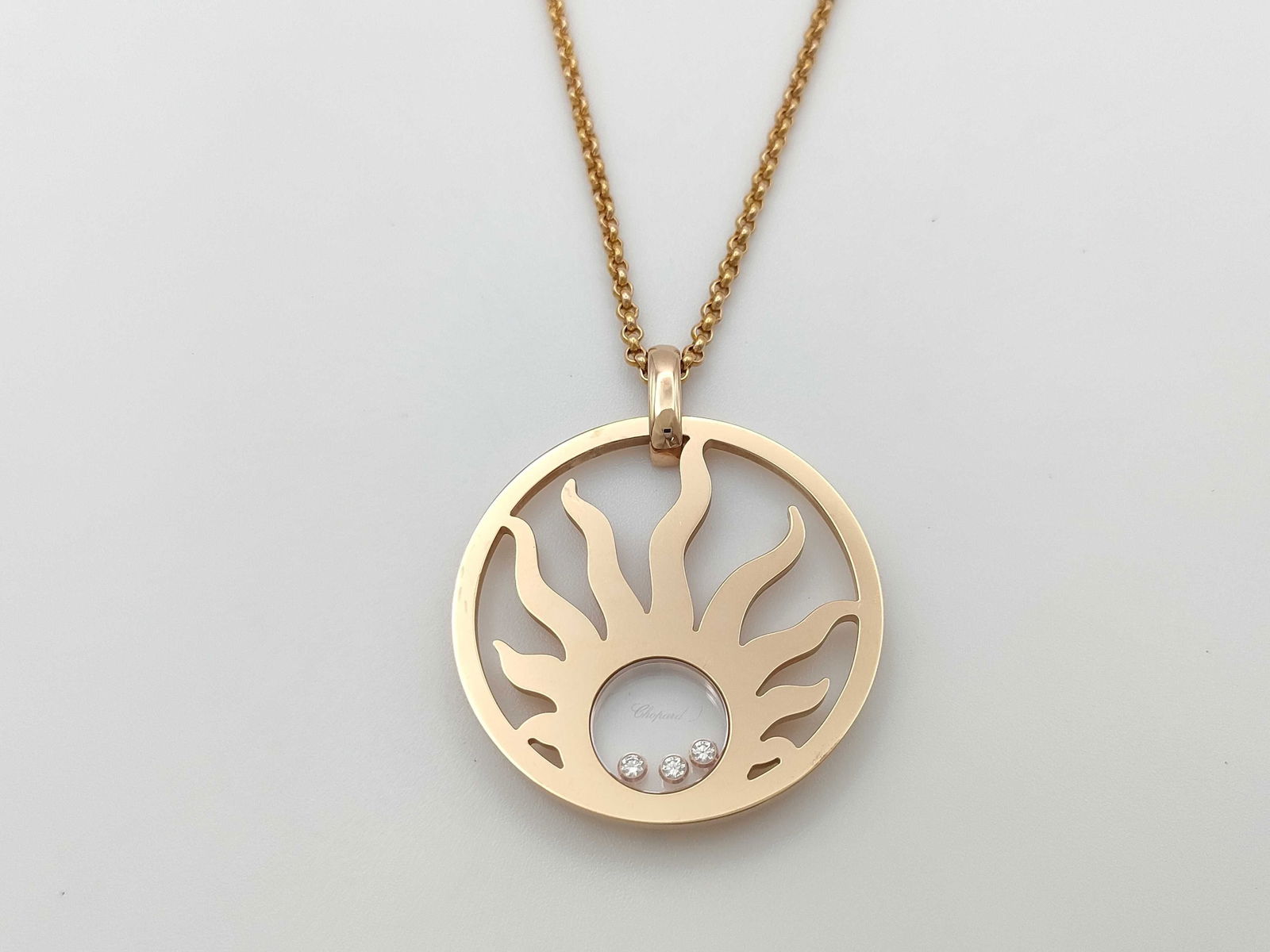 Chopard Happy Sun Floating Diamond 18K Yellow Gold Pendant Necklace: Iconic Chopard Happy Sun necklace crafted in solid 18K yellow gold, featuring a circular sunburst pendant with the collection's signature floating diamond elements enclosed within sapphire crystal. Th