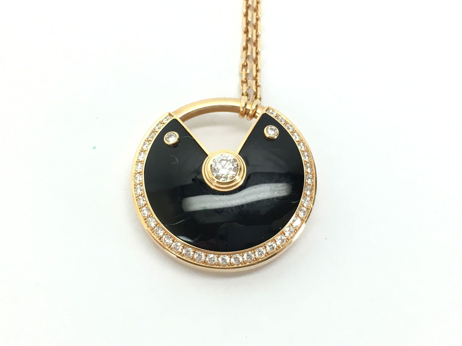 Cartier Amulette Large De Cartier Black Onyx & Diamond 18K Rose Gold Pendant Necklace: This elegant Cartier Amulette de Cartier pendant necklace is crafted in solid 18K gold and features a striking black onyx motif accented with brilliant diamonds. The bold circular design symbolizes pr