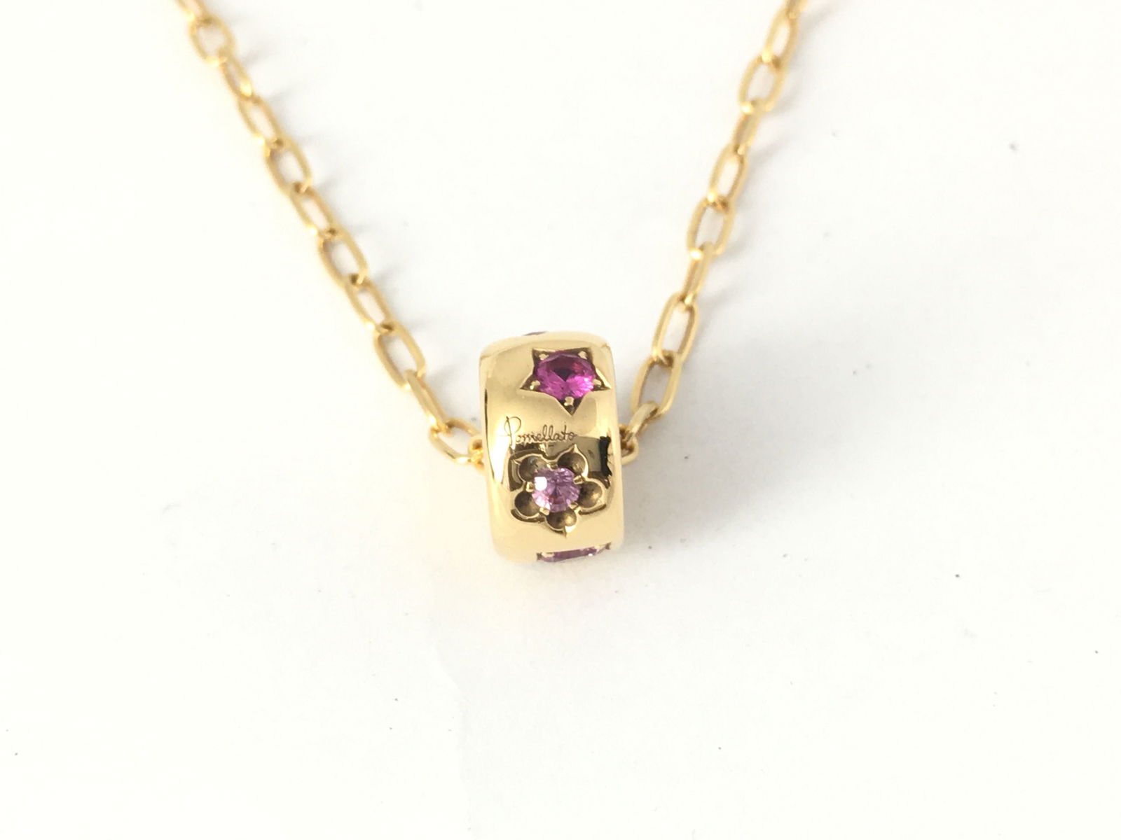 Pomellato Ruby Sapphire 18K Yellow Gold Pendant Necklace: Elegant Pomellato pendant necklace crafted in polished 18K yellow gold, featuring vibrant ruby and sapphire gemstones set within a sculptural cylindrical pendant. The colorful stones create a refined