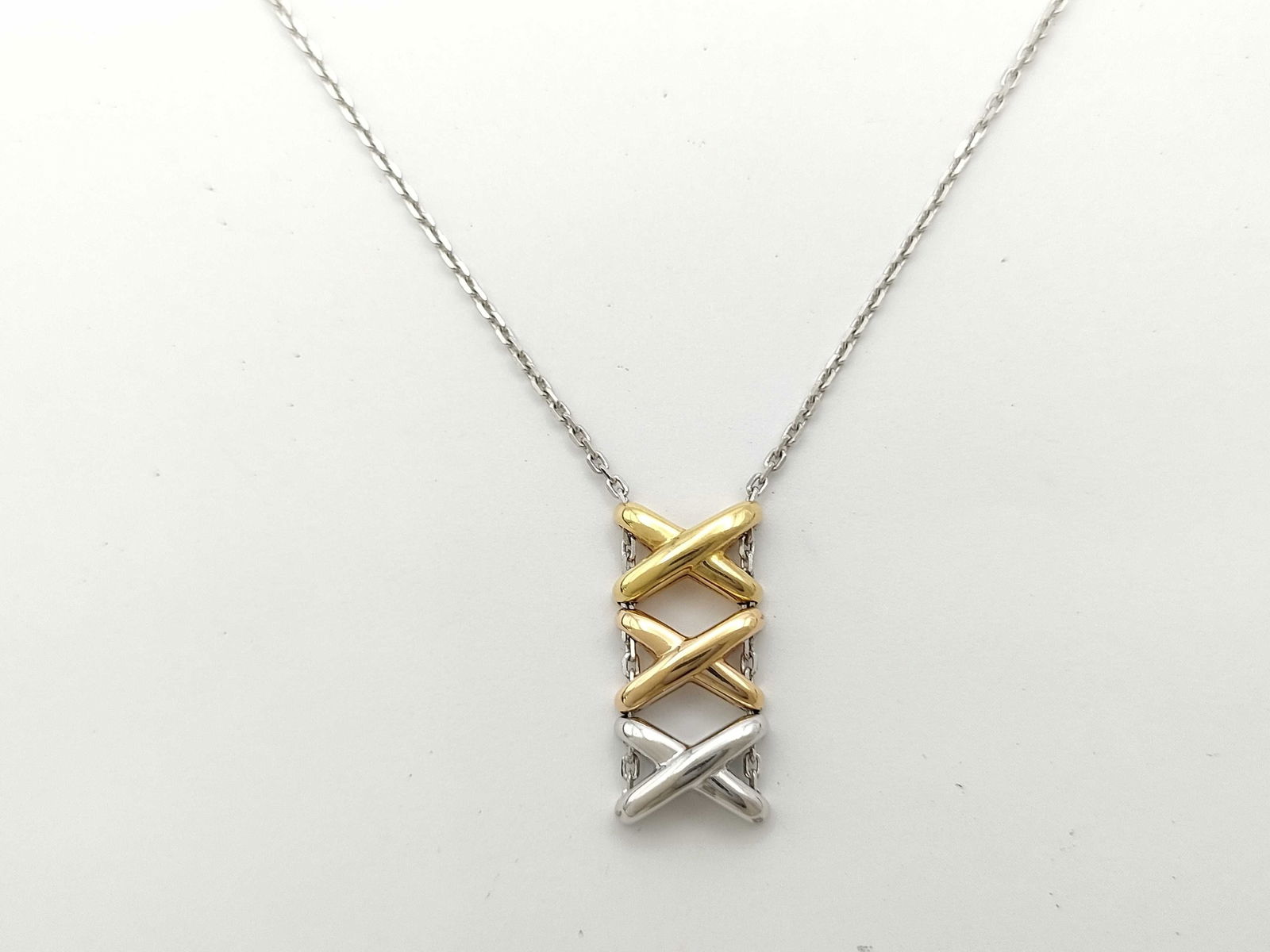 Chaumet Lian X Tri Tone 18K Rose Yellow & White Gold Pendant Necklace: This elegant Chaumet Lian pendant necklace is crafted in solid 18K tri-tone gold, featuring rose gold, yellow gold, and white gold intertwined in the Maison's iconic cross motif design. The refined fo