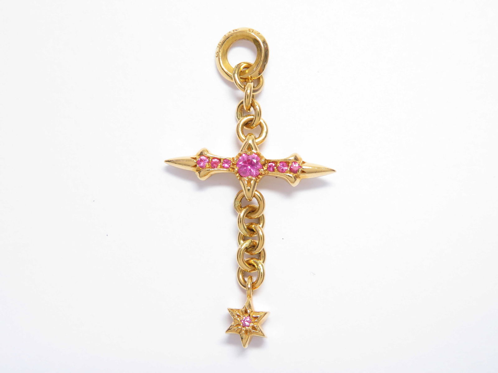 Chrome Hearts Raleigh Cross Pink Sapphire 22K Charm Pendant: Description: Striking Raleigh cross charm pendant crafted in solid gold, featuring Chrome Hearts? signature elongated cross design accented with vivid pink sapphires throughout the center and arms. Th