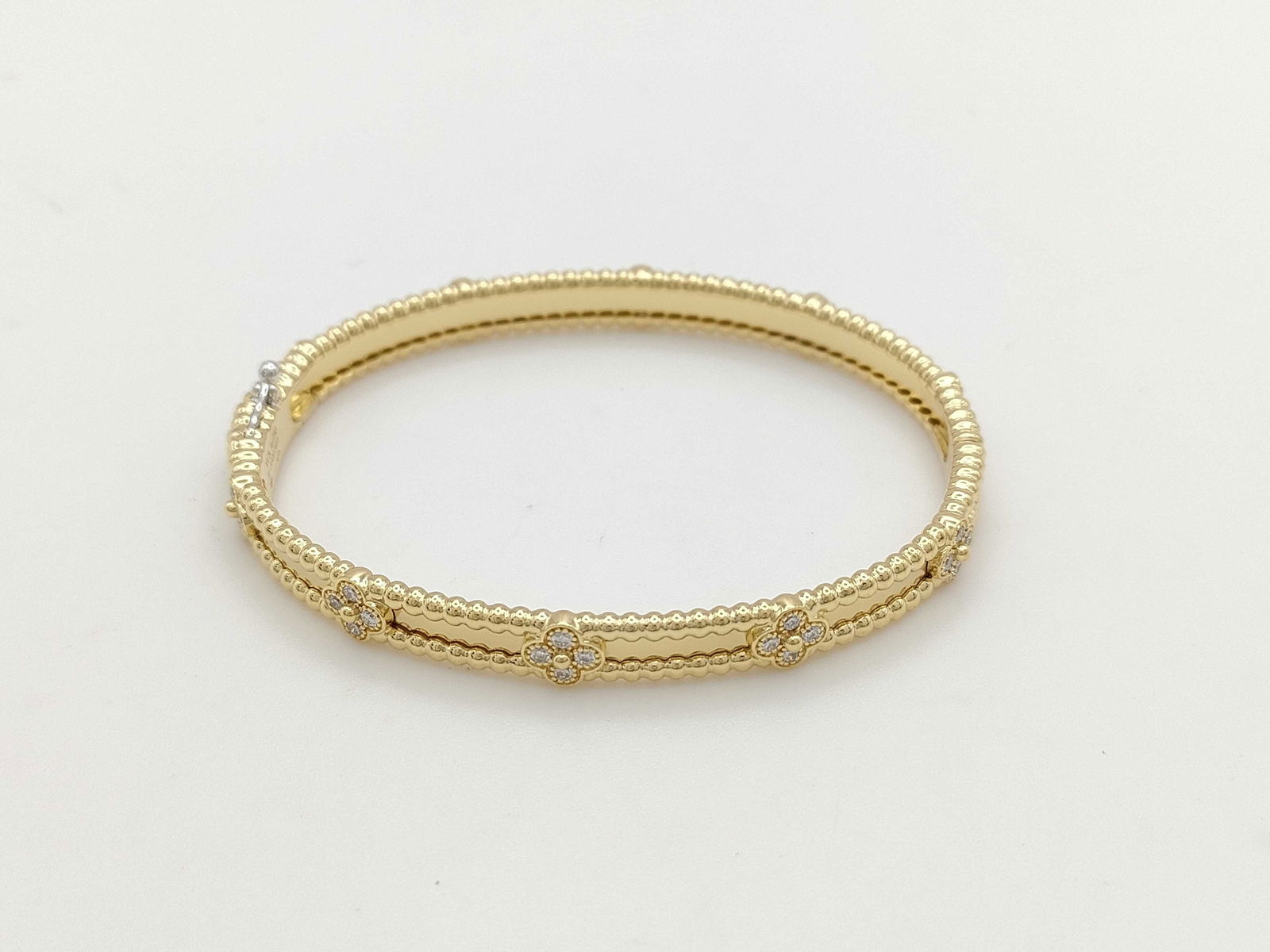Van Cleef & Arpels Perlee Sweet Clover Diamond 18K Yellow Gold Bangle Bracelet: This elegant Van Cleef & Arpels Perlee Sweet Clover bangle bracelet is crafted in solid 18K gold and features the signature clover motif accented with brilliant diamonds. The refined design showcases
