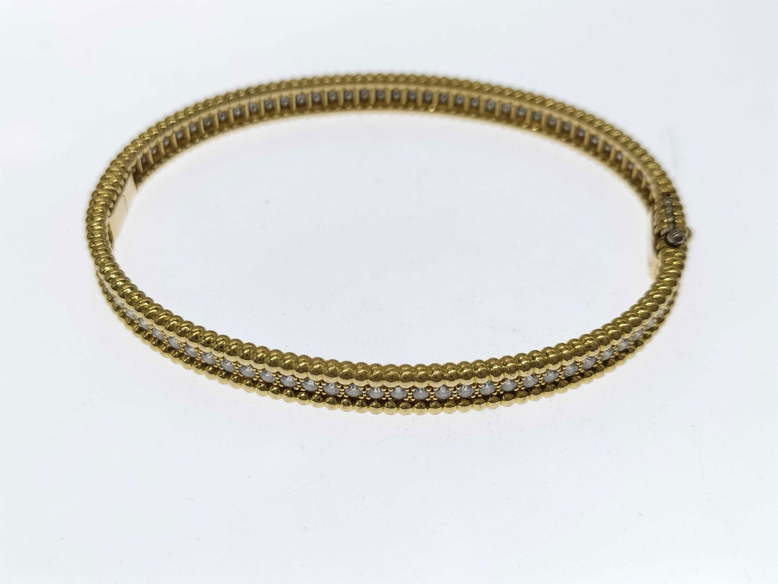 Van Cleef & Arpels Perlee Diamond 18K Gold Bangle Bracelet: This elegant Van Cleef & Arpels Perlee bangle bracelet is crafted in solid 18K gold and features brilliant diamonds set within the collection's signature beaded gold design. The refined form reflects