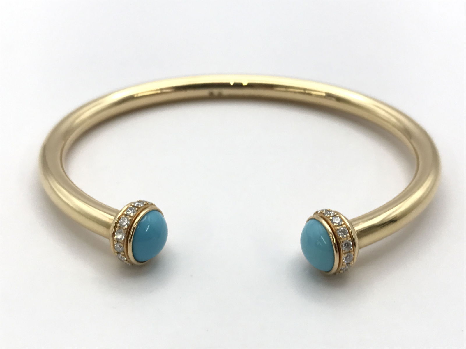 Piaget Possession Turquoise Diamond 18K Rose Gold Bangle Bracelet: Elegant Piaget Possession bangle bracelet crafted in solid 18K rose gold featuring turquoise cabochon terminals accented with brilliant diamonds. The open cuff design highlights the Maison’s iconic