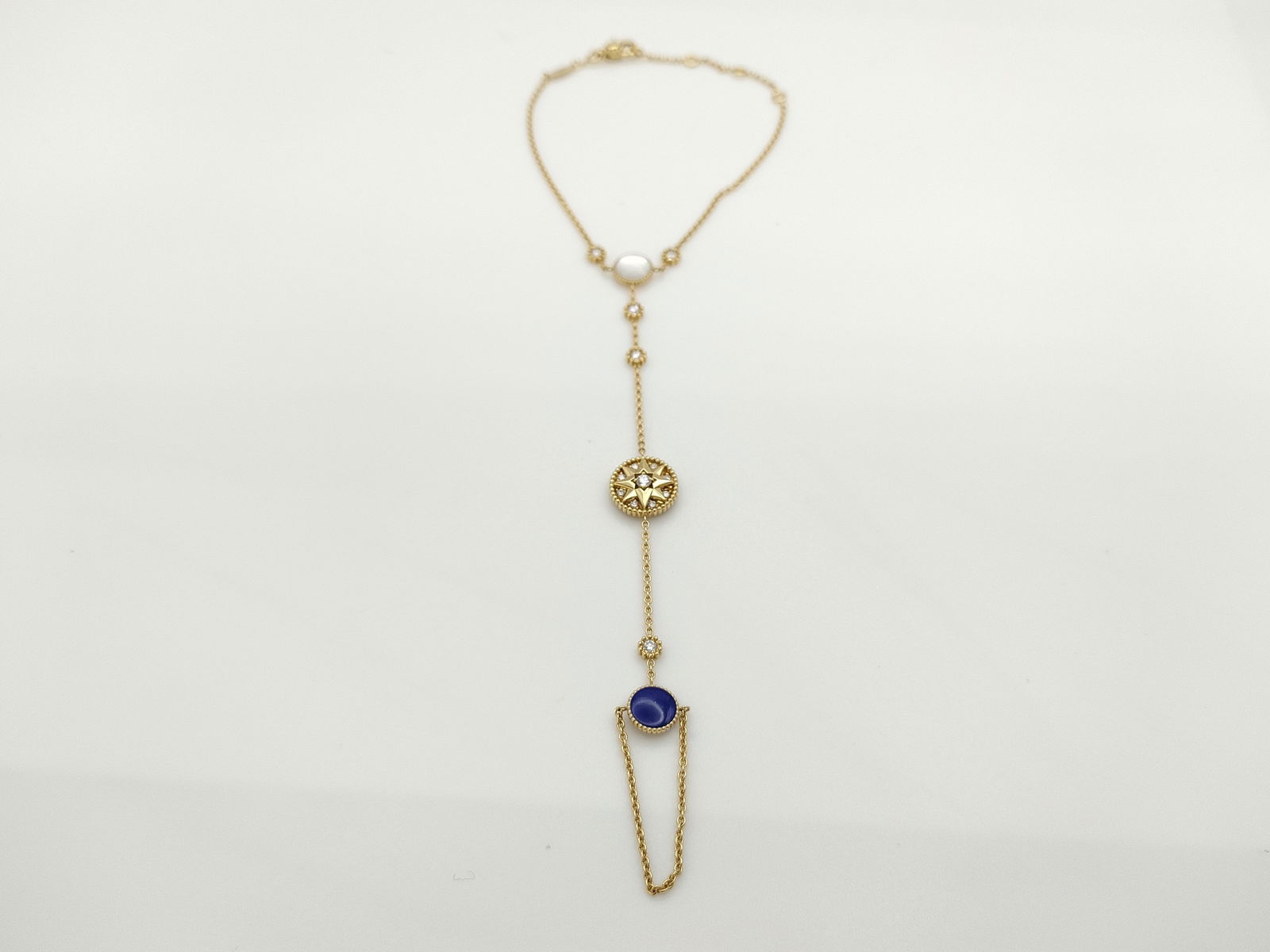 Dior Rose des Vents MOP Lapis Diamond 18K Yellow Gold Hand Chain Bracelet: Elegant Dior Rose des Vents hand chain bracelet crafted in 18K yellow gold featuring the Maison’s iconic compass rose motif. The design is accented with luminous mother of pearl and deep blue lapis