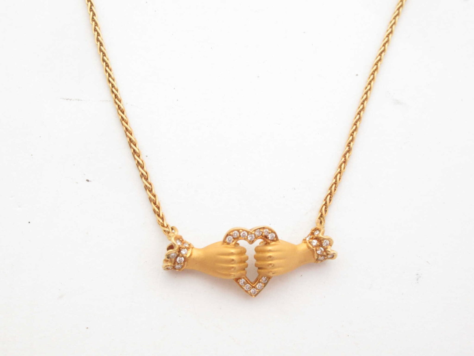 Carrera y Carrera Calette Carella Diamond 18K Yellow Gold Necklace: Distinctive Carrera y Carrera necklace crafted in solid 18K yellow gold featuring the brand’s signature sculptural artistry. The pendant displays two finely sculpted hands forming a heart motif acce