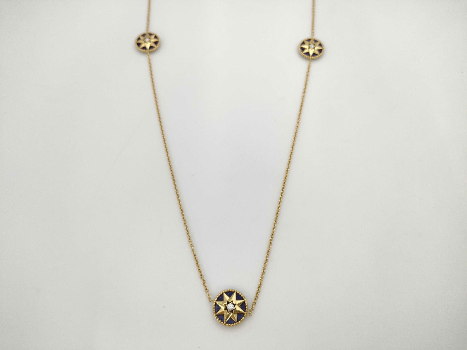 Dior Rose des Vents Lapis Lazuli Diamond 18K Yellow Gold 9 Motif Necklace: Elegant Dior Rose des Vents necklace crafted in 18K yellow gold featuring nine compass rose medallions from the iconic collection. The motifs are set with deep blue lapis lazuli and accented with cent