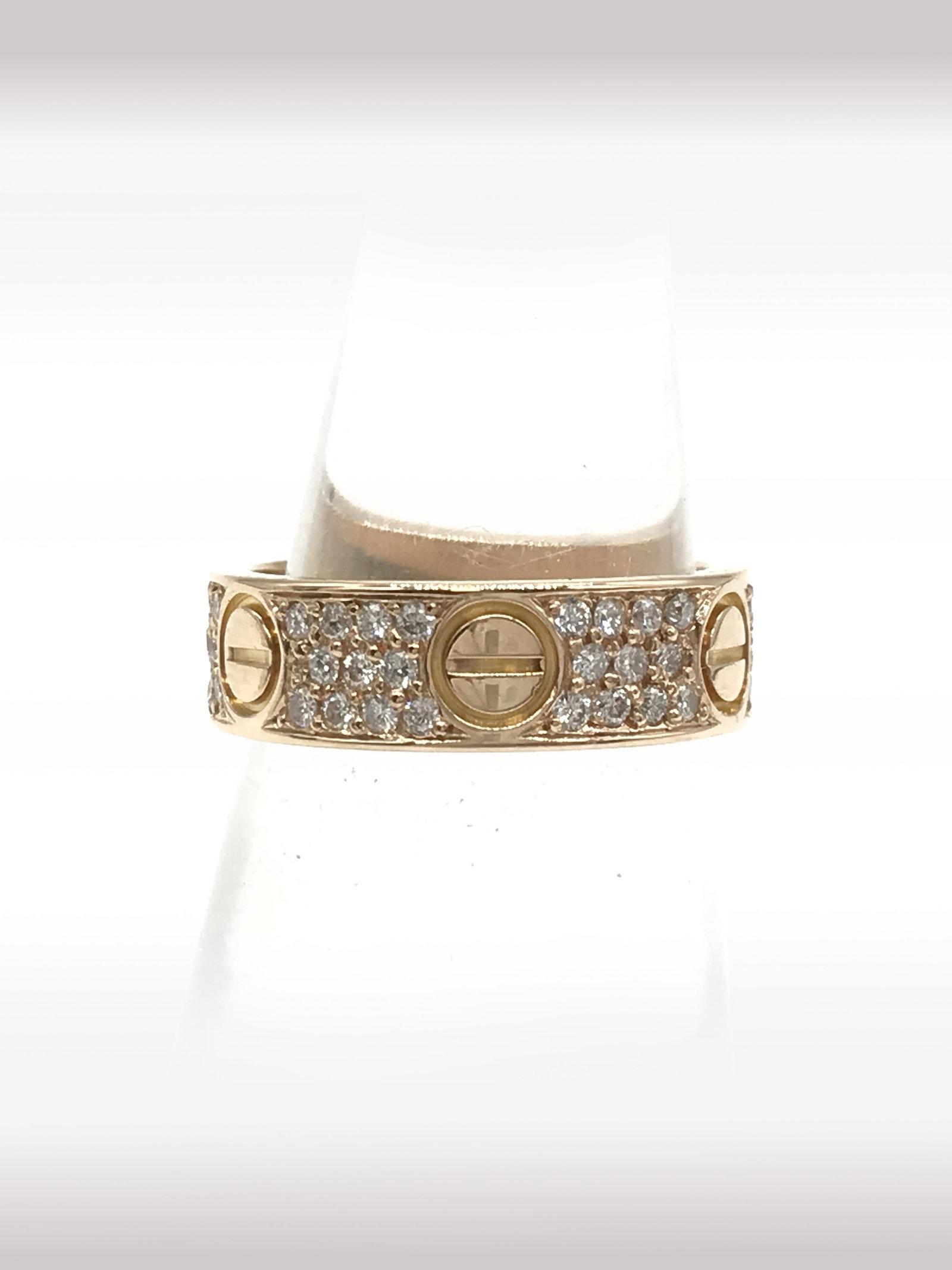 Cartier Love Diamond Pave 18K Rose Gold Band Ring: Description: Iconic Cartier Love band ring crafted in 18K rose gold, featuring the signature screw motif design accented with pavé set natural diamonds throughout the band. The warm tone of the r