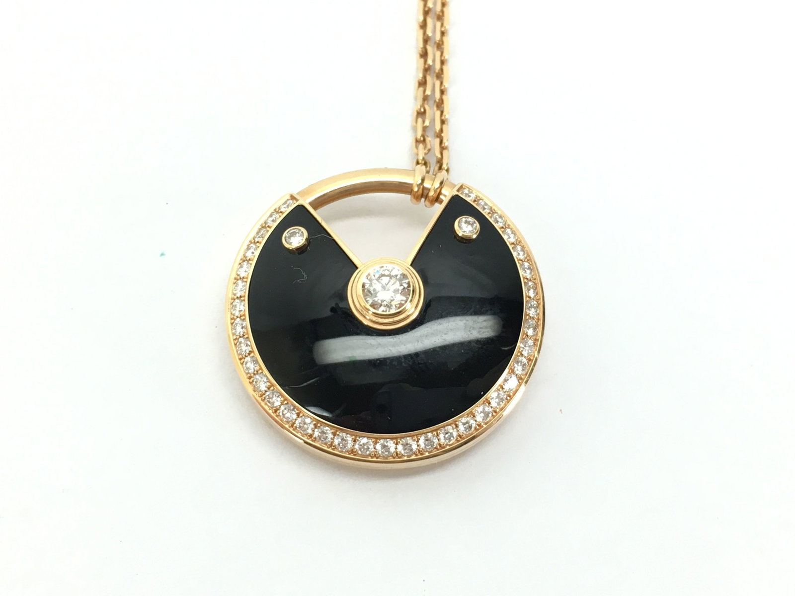 Cartier Amulette Large De Cartier Black Onyx & Diamond 18K Rose Gold Pendant Necklace: Description: This elegant Cartier Amulette de Cartier pendant necklace is crafted in solid 18K gold and features a striking black onyx motif accented with brilliant diamonds. The bold circular design 
