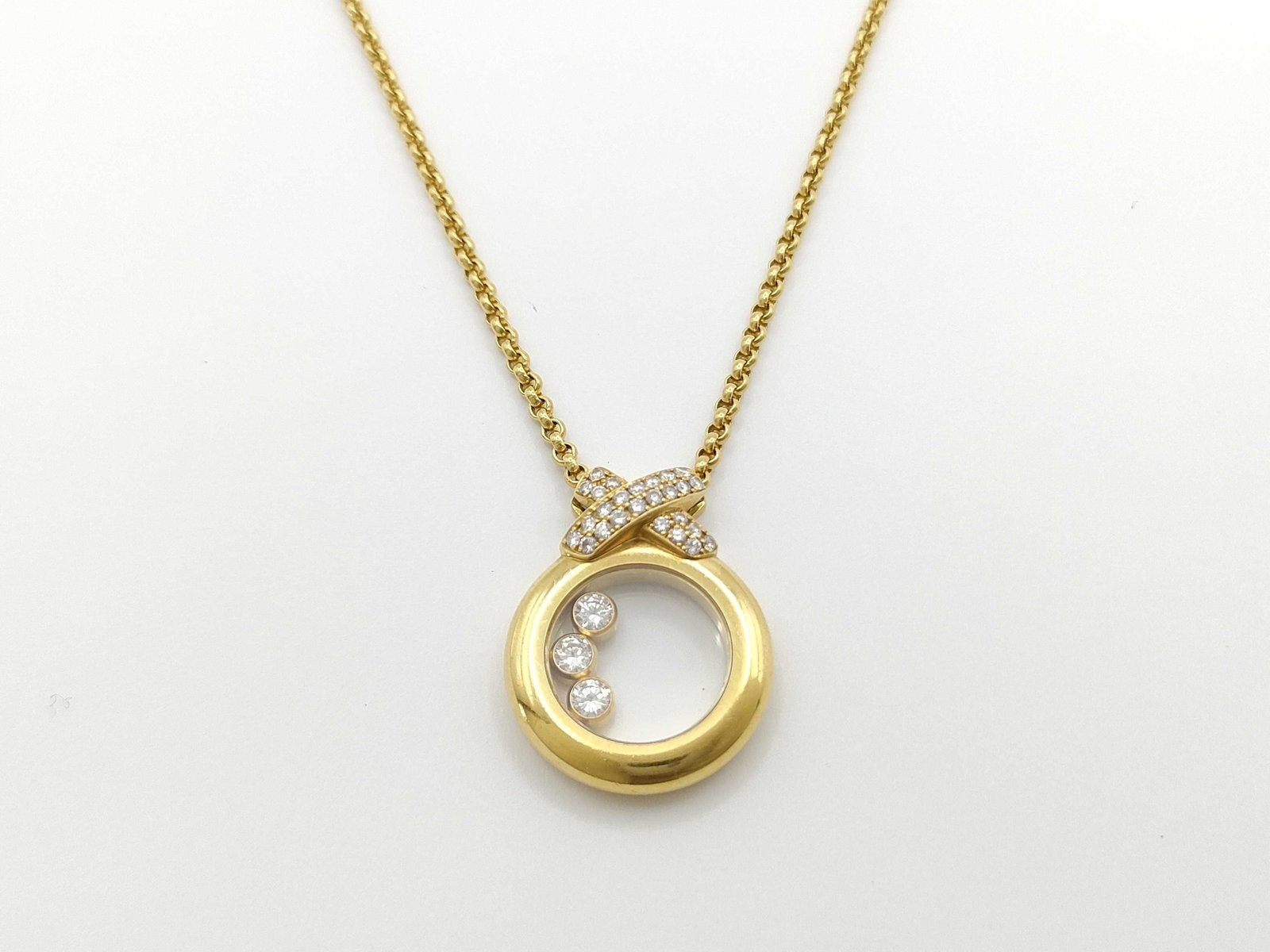 Chopard Happy Diamonds Ribbon 18K Yellow Gold Diamond Pendant Necklace: Description: This elegant Chopard Happy Diamonds necklace is crafted in solid 18K yellow gold and features the iconic floating diamond design within a polished circular pendant. The pendant is