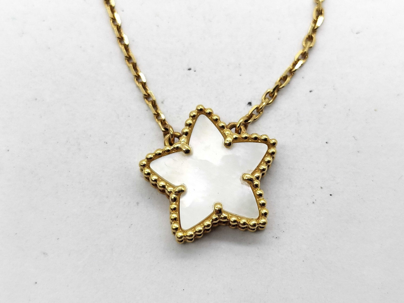 Van Cleef & Arpels Vintage Alhambra Star Motif White Mother of Pearl 18K Yellow Gold Pendant: Description: Van Cleef & Arpels Vintage Alhambra Star Motif pendant necklace crafted in 18K yellow gold and featuring a white mother of pearl motif. Combining the Maison's celebrated Alhambra desi