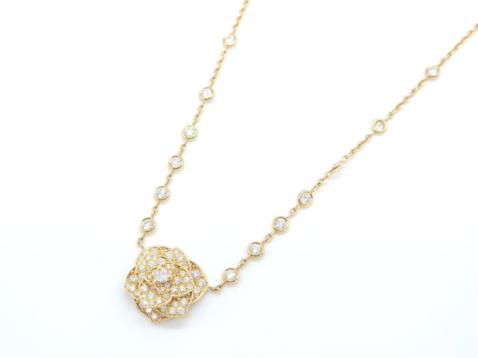 Piaget Large Rose Diamond 18K Yellow Gold Pendant Necklace: Description: Elegant Piaget necklace crafted in solid 18K yellow gold featuring a sculptural rose motif set with numerous brilliant diamonds. The refined floral centerpiece is complemented by diamond 
