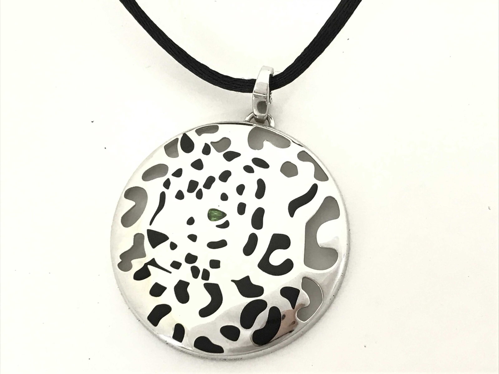 Cartier Panthere Black Lacquer Green Tsavorite Eyes 18K White Gold Cord Medallion Pendant Necklace: Description: Cartier Panthere medallion pendant necklace crafted in 18K white gold and featuring a black lacquer panther motif accented with green tsavorite eyes. Suspended from a cord necklace, the p
