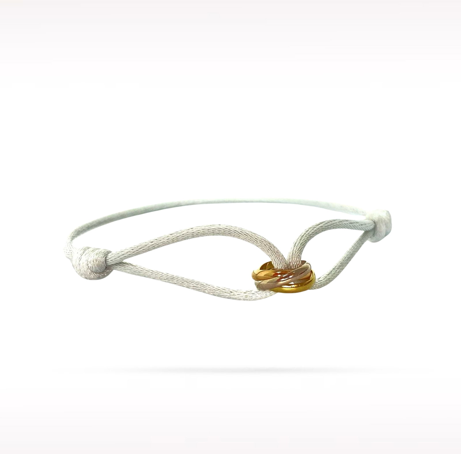 Cartier Trinity 18K Yellow White and Rose Gold Rings Adjustable White Cord Bracelet: Description: Cartier Trinity bracelet crafted in 18K yellow, white, and rose gold featuring the iconic Trinity rings on an adjustable white cord. From Cartier's celebrated Trinity collection, this ele
