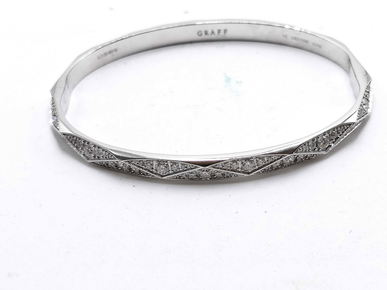 Graff Signature Diamond 18K White Gold Bangle Bracelet: Description: Elegant Graff Signature bracelet crafted in 18K white gold and set with brilliant cut pave diamonds. The bracelet features a refined geometric design with intersecting diamond set segment