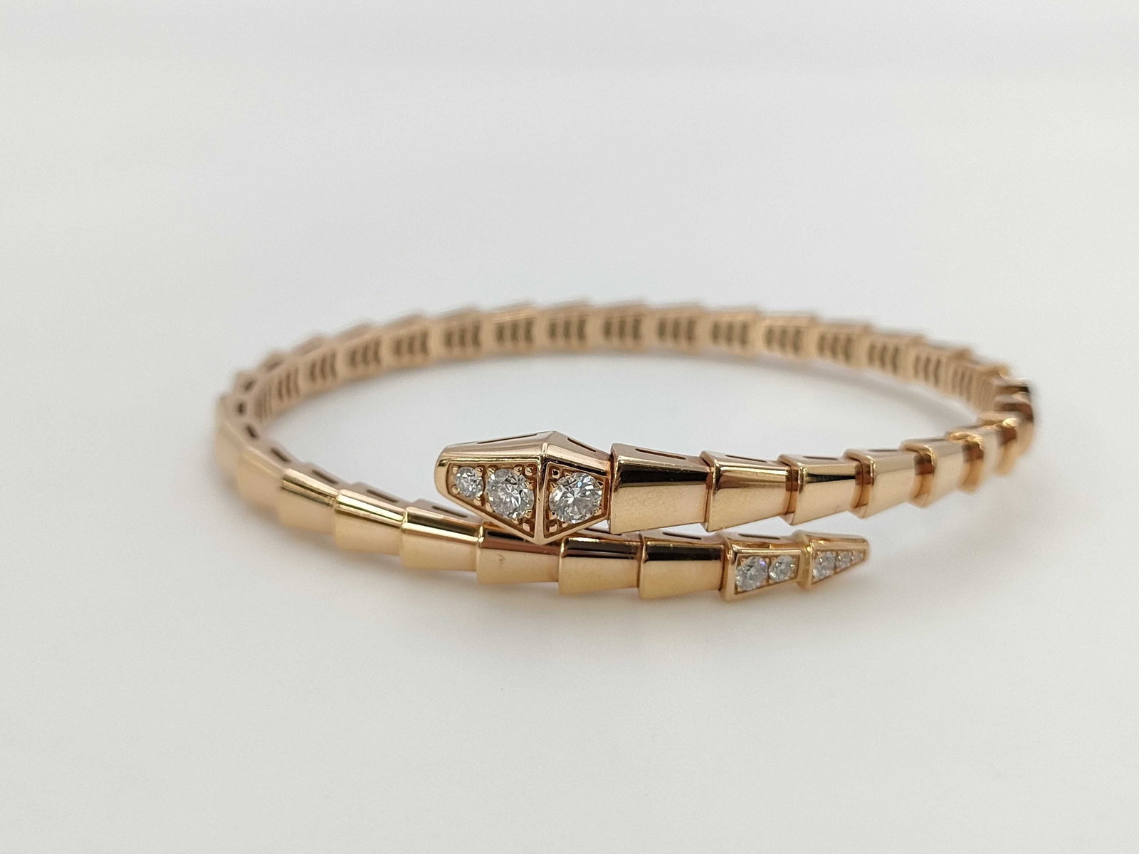 Bvlgari Serpenti Half Pave Diamond 18K Rose Gold Bangle Bracelet: Description: Bvlgari Serpenti bangle bracelet crafted in 18K rose gold and fully accented with pave set natural diamonds. Featuring the collection's iconic serpent design, the bracelet is highlighted 