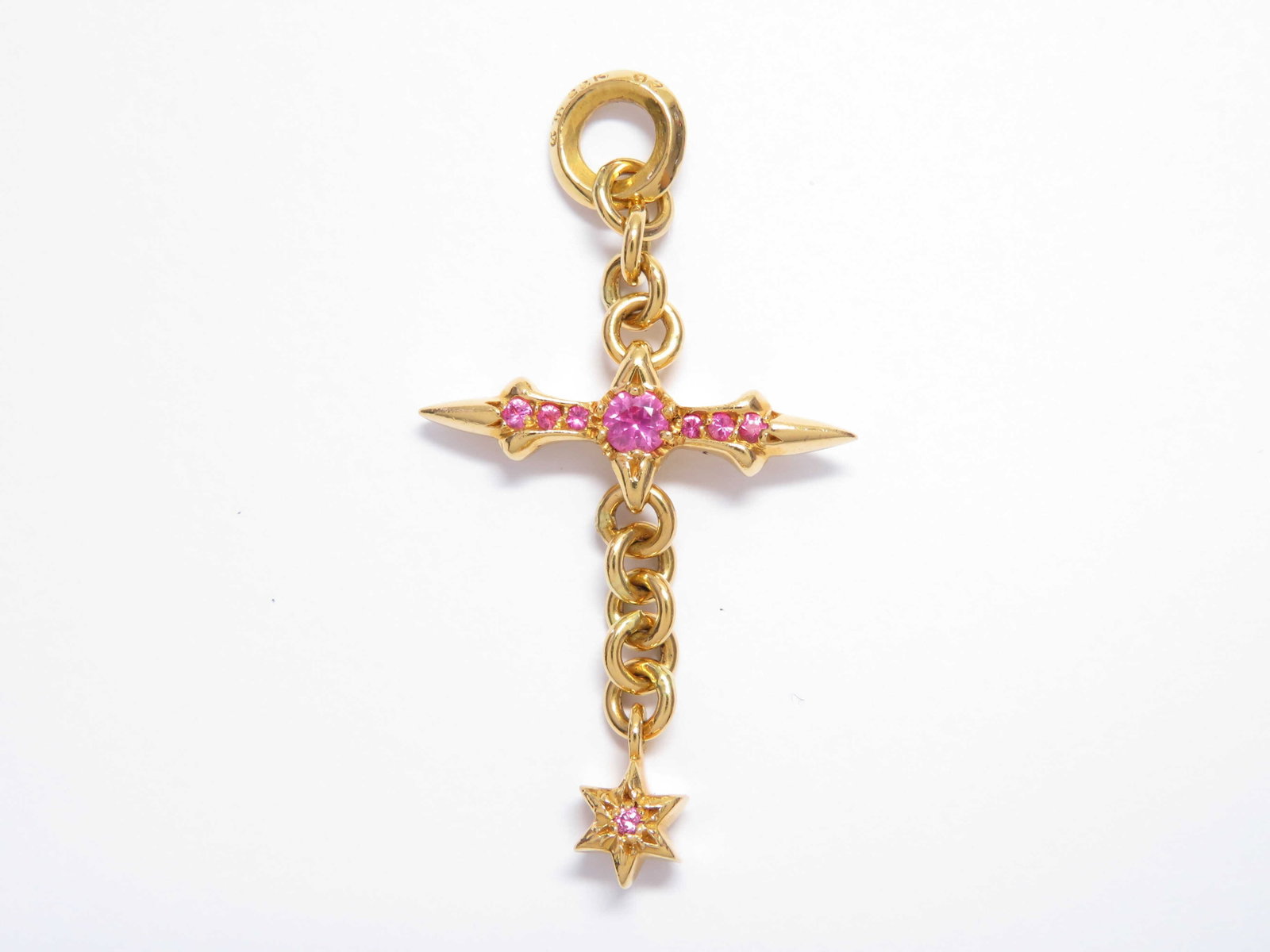 Chrome Hearts Raleigh Cross Pink Sapphire 22K Charm Pendant: Description: Striking Raleigh cross charm pendant crafted in solid gold, featuring Chrome Hearts’ signature elongated cross design accented with vivid pink sapphires throughout the center and ar