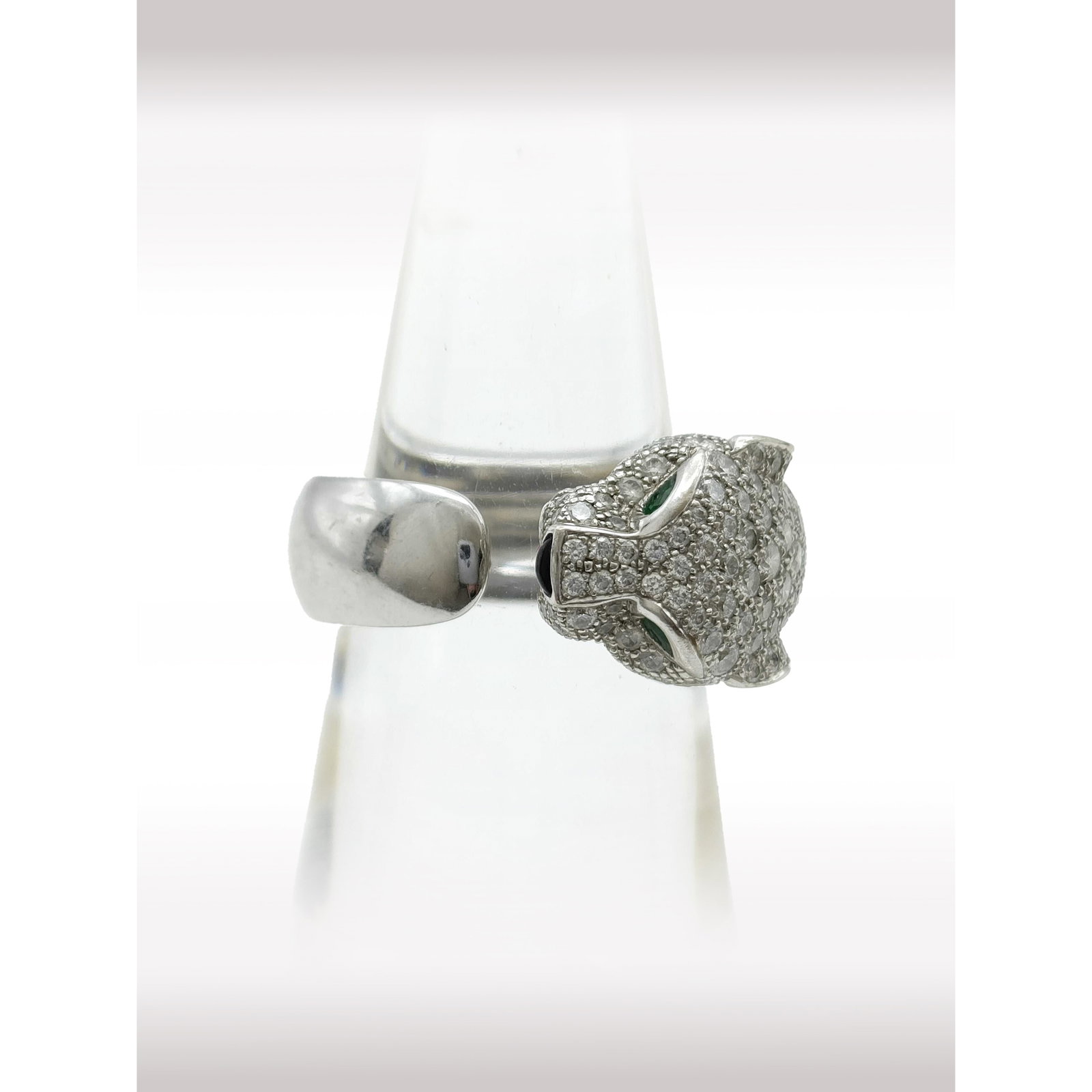 Cartier Panthere Diamond Pave Emerald Onyx 18K White Gold Ring: Description: Exceptional Cartier Panthere ring crafted in 18K white gold, featuring the Maison signature panther design fully accented with pave set diamonds. The eyes are set with vivid emeralds,