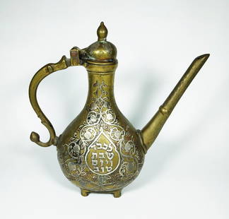 A Judaica jug for washing ones hands - Damascene work: A brass kettle decorated with silver , on one side writing- "?? ????? ?????" and on the other "???? ??? ???? ???" on the lid a engraving in the shape of the Kohanim's hands height- 23 cm