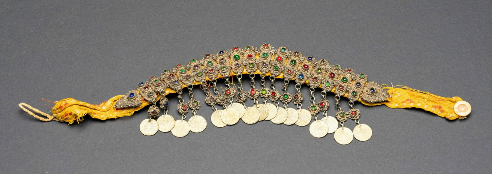 A ottoman gilded silver and semi precious stone Islam: The silver head piece is comprised of oval shaped filigree plaques. Each plaque is set with three glass stones. on the bottom of the piece hanging from small silver ornaments are silver Ottoman coins 
