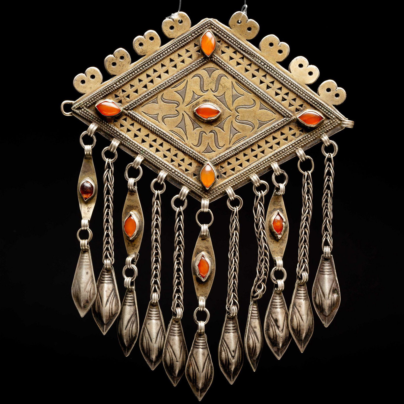 A silver gilt chest ornament - Turkestan,Teke islamic: The plaque is finely gilded and set with carnelian stones throughout. punched Tassels hang from the bottom of the plaque. The item is cut, pierced, punched, soldered and gilded. dimensions:8*13 cm