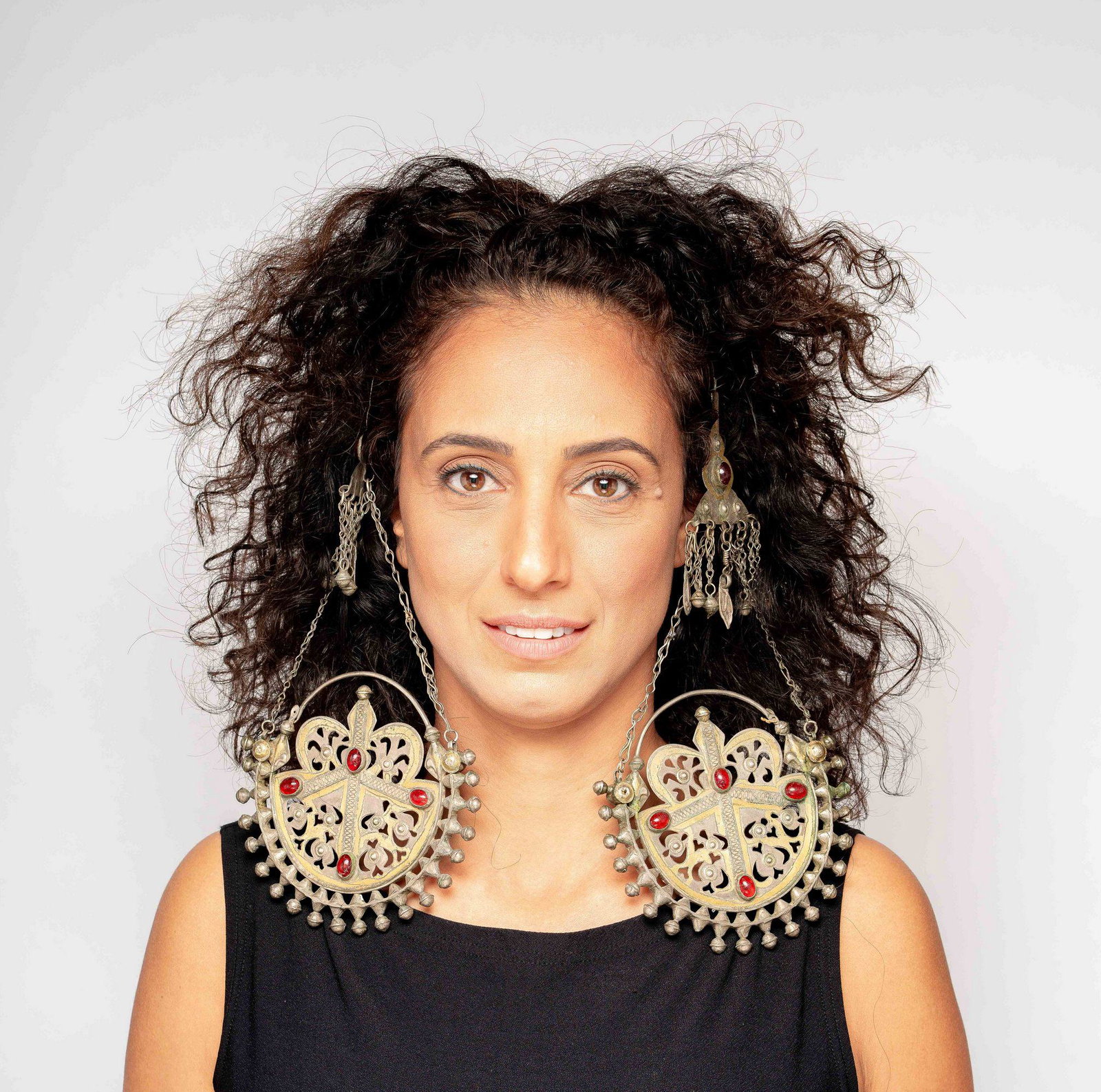 large parcel gilt silver earrings Turkmen Islamic: The large and impressive temple pendants are comprised of three components. The upper plaque which is cut, gilded and set with a red cabochon. Tassels hang from the bottom. Two chains connect it to th