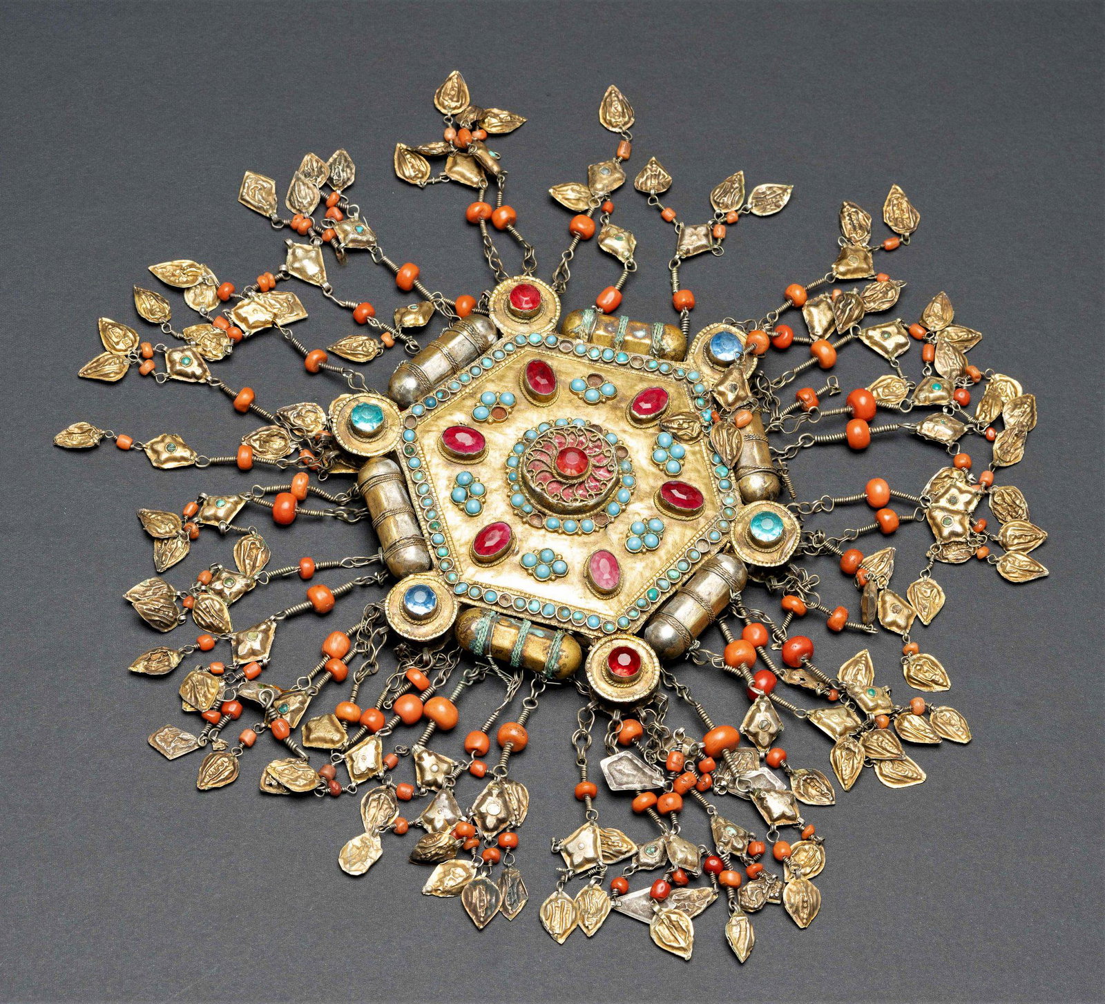 gilded silver coral head piece Bukhara islamic Jewish: The ornament is adorned with fine filigree work. Set with turquoise,and red and blue stones. Cylindrical and circular elements surround the hexagonal shaped body. Tassels incorporated with large coral