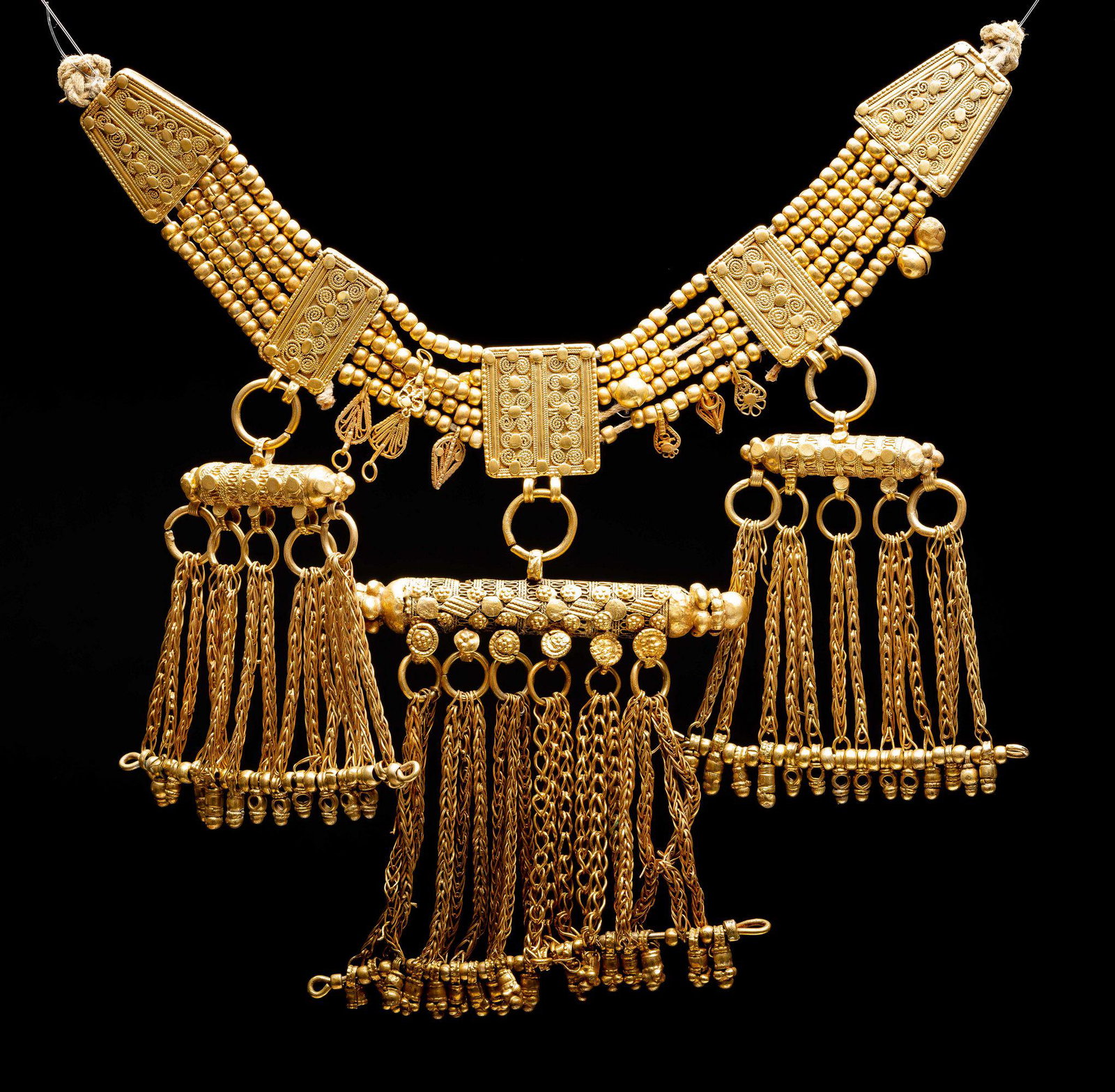 Gilded and worked Lazem necklace- Yemen Jewish Islamic: The necklace is comprised of two triangular plaques (tadarif) with rows of gilded beads connecting to the rectangular shaped plaques. Fine filigree work covers the gilded plaques. Below are three amul